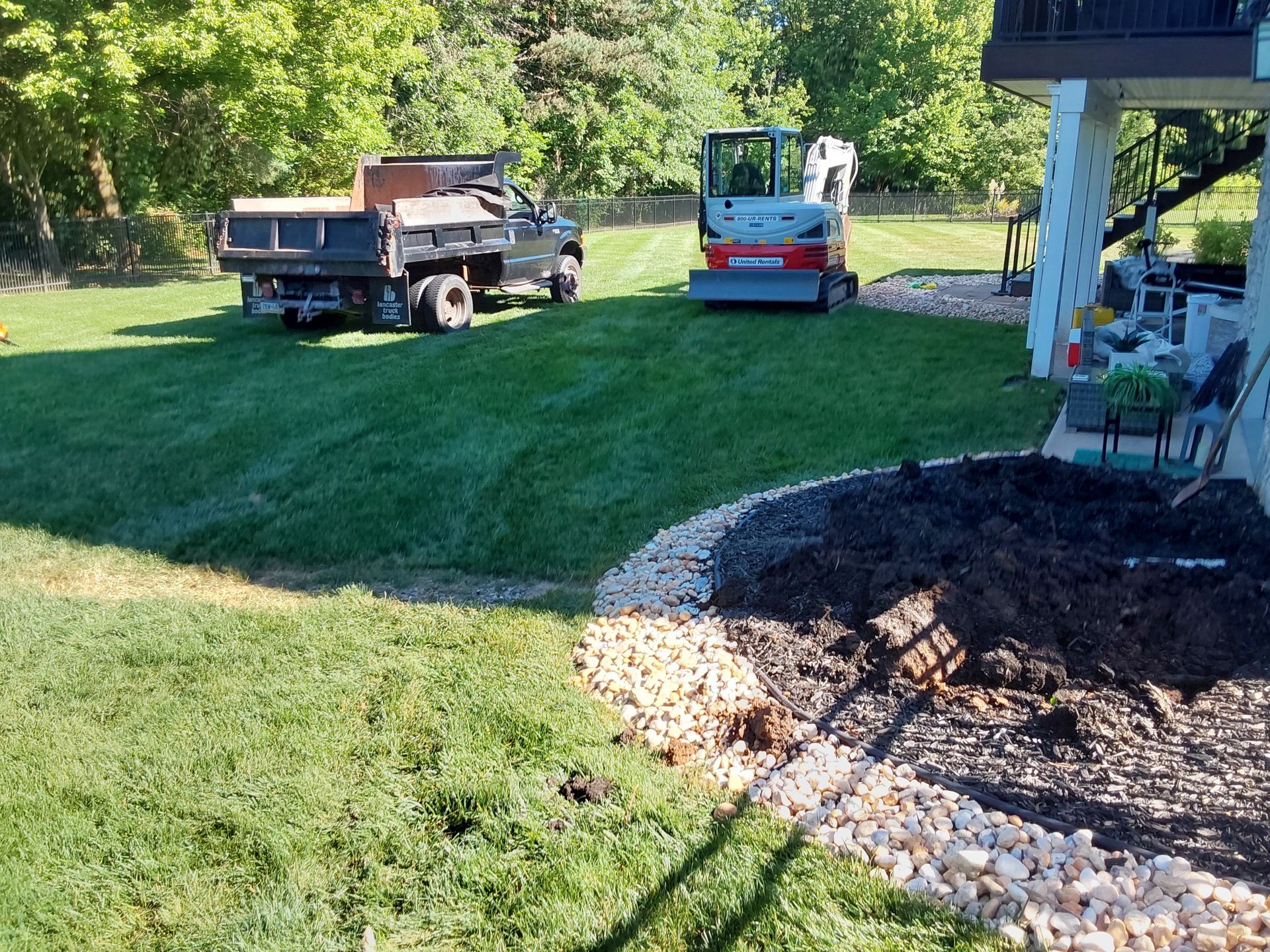 a dump truck is parked in the grass next to a small excavator