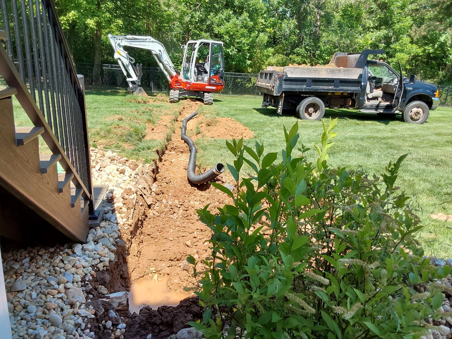 an excavator is digging a hole in the ground next to a dump truck