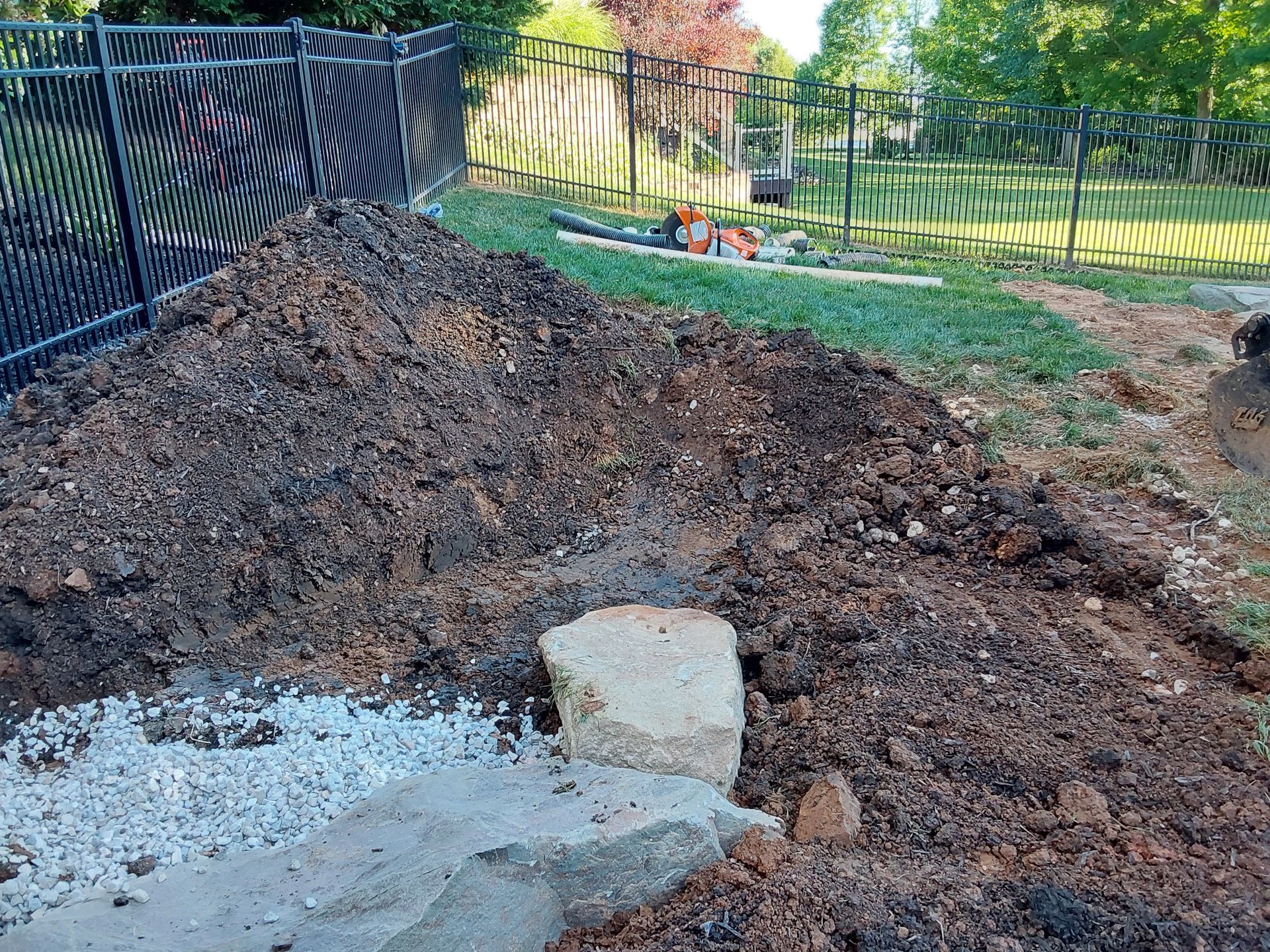 a pile of dirt and rocks in a yard next to a fence