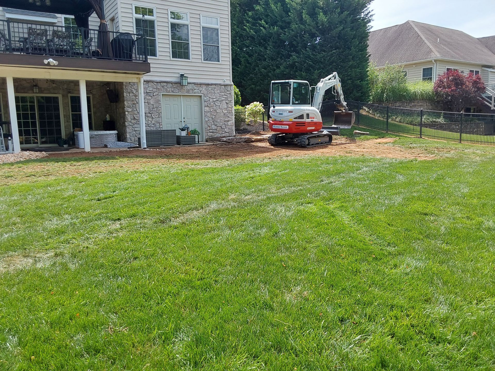 an excavator is sitting in the grass in front of a house