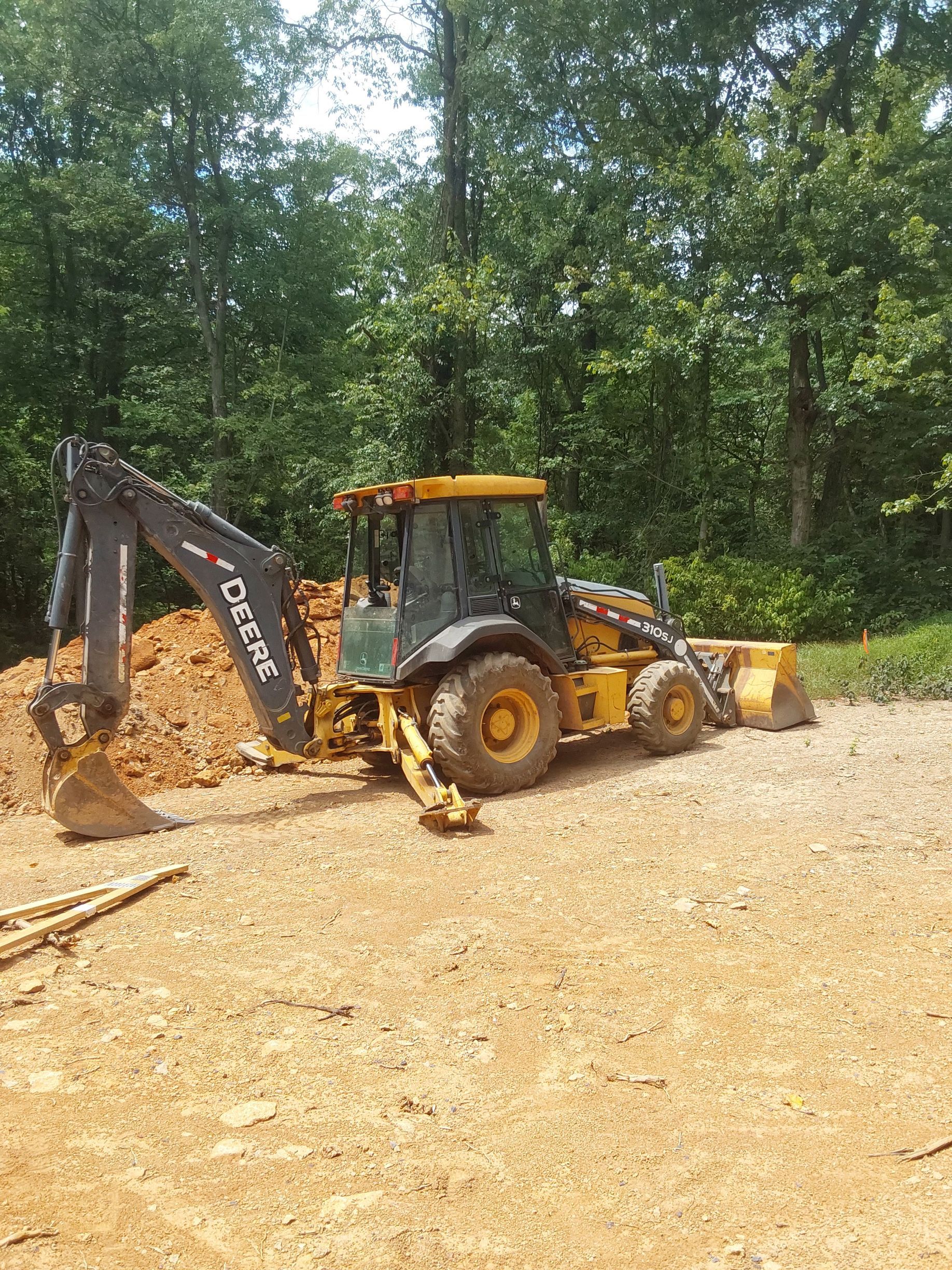a yellow backhoe is sitting on top of a dirt field
