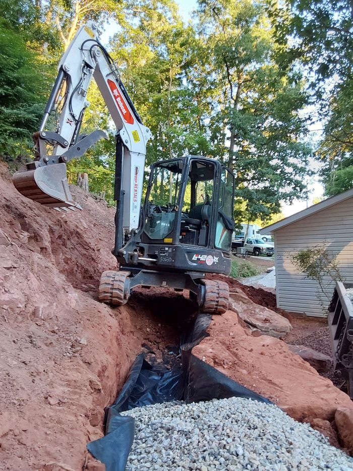 a bulldozer is digging a hole in the ground next to a house