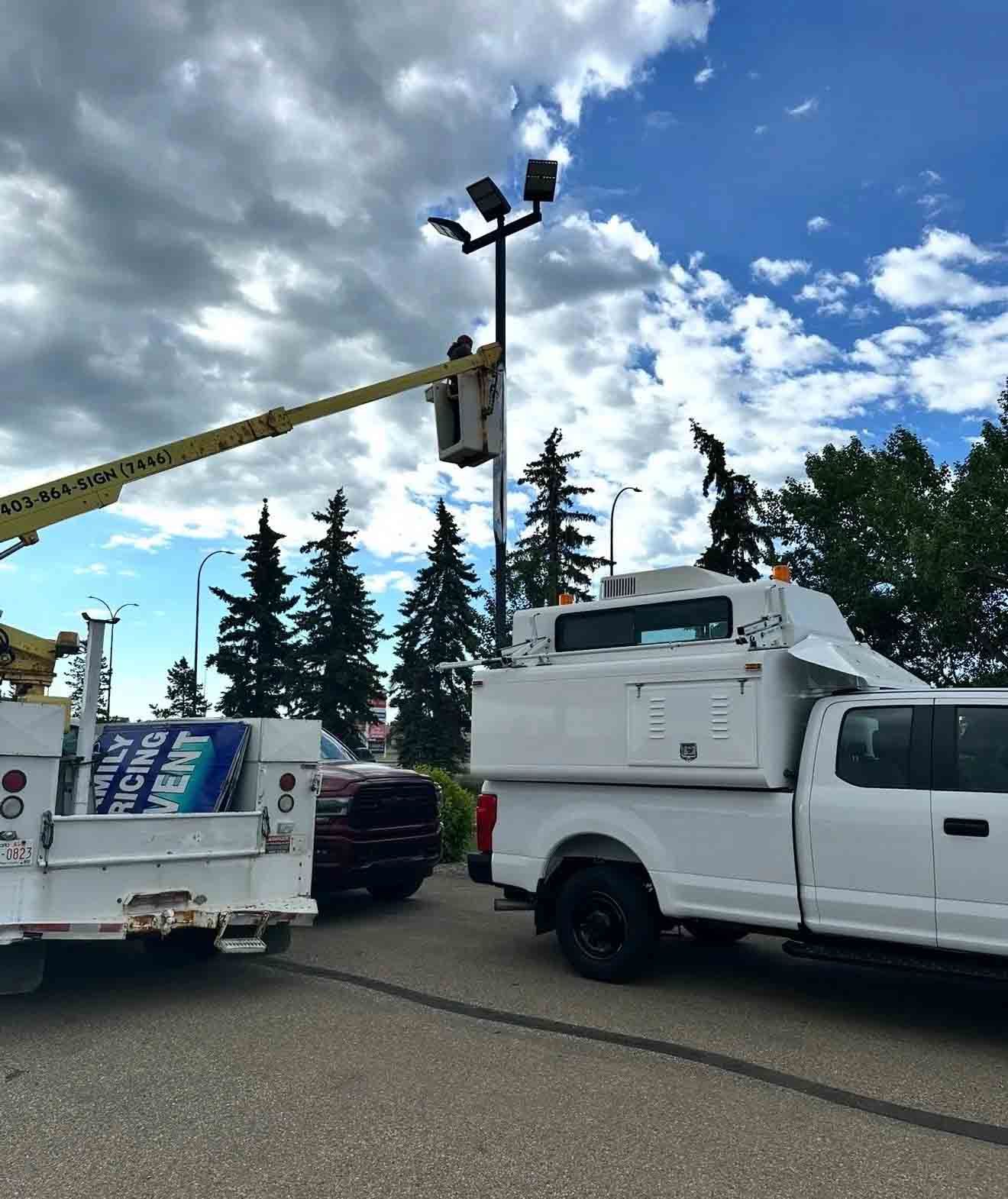Bucket truck extended beside illuminated pylon sign at night