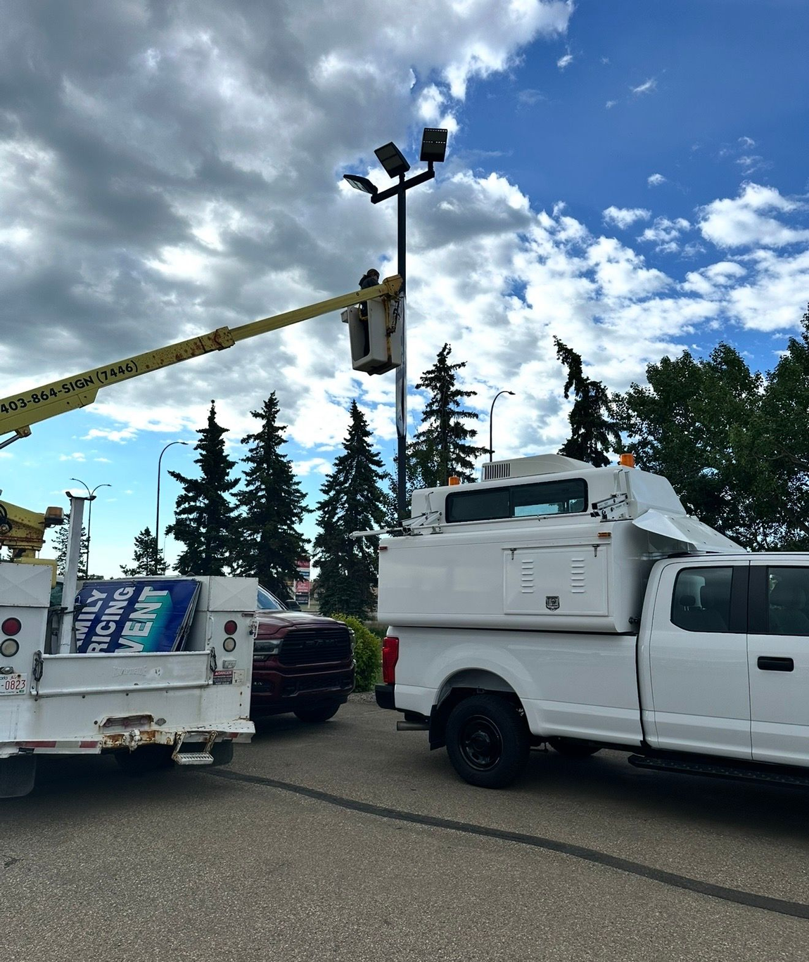 Bucket truck extended beside illuminated pylon sign at night