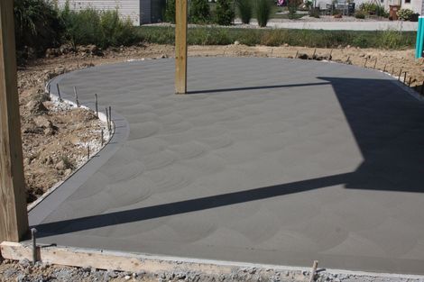 Stacked gray concrete retaining wall blocks on a sloped grassy site, with gravel in front.