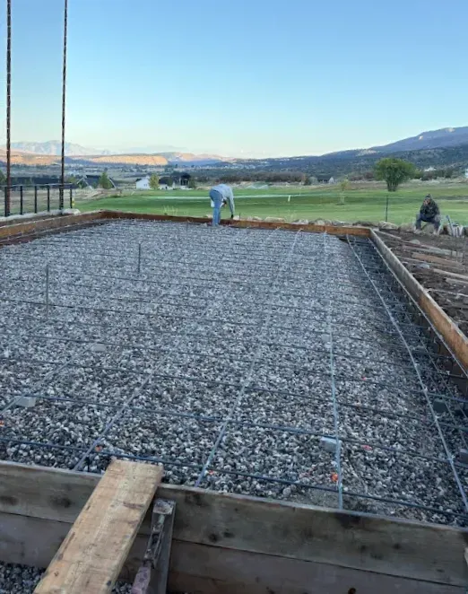 Person smoothing a curved concrete walkway beside a house during construction