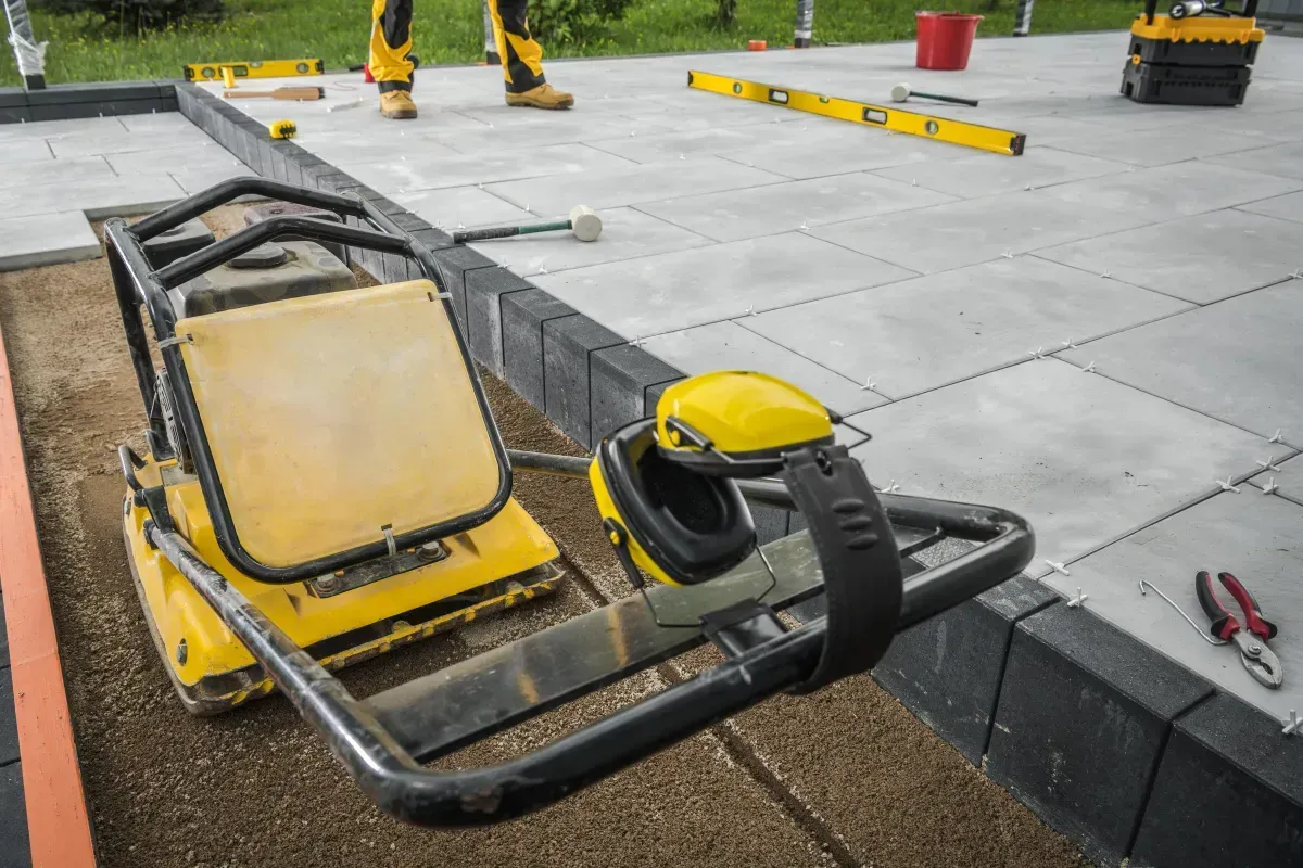 Yellow wheelbarrow on a concrete construction site beside paving slabs and tools