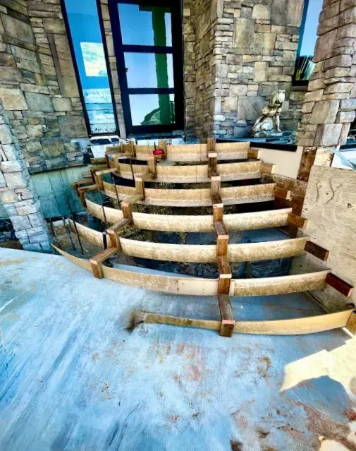 Stone steps under construction in a stone-and-glass interior with blue flooring and large windows