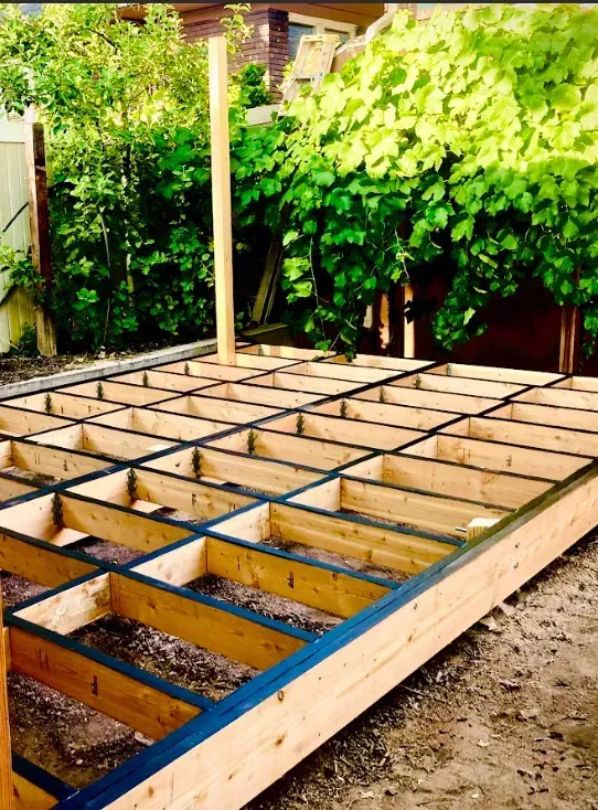 Wooden deck frame under construction in a sunny backyard garden