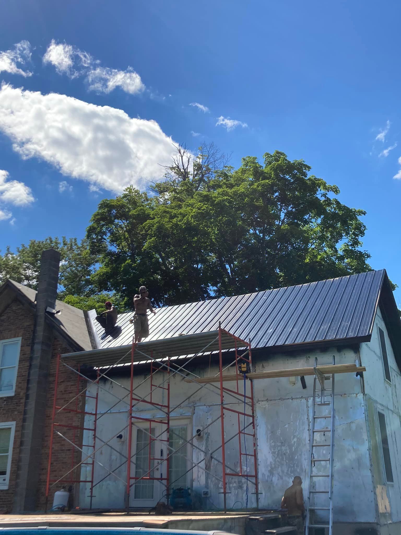 Partly renovated house with scaffolding and ladder under a blue sky