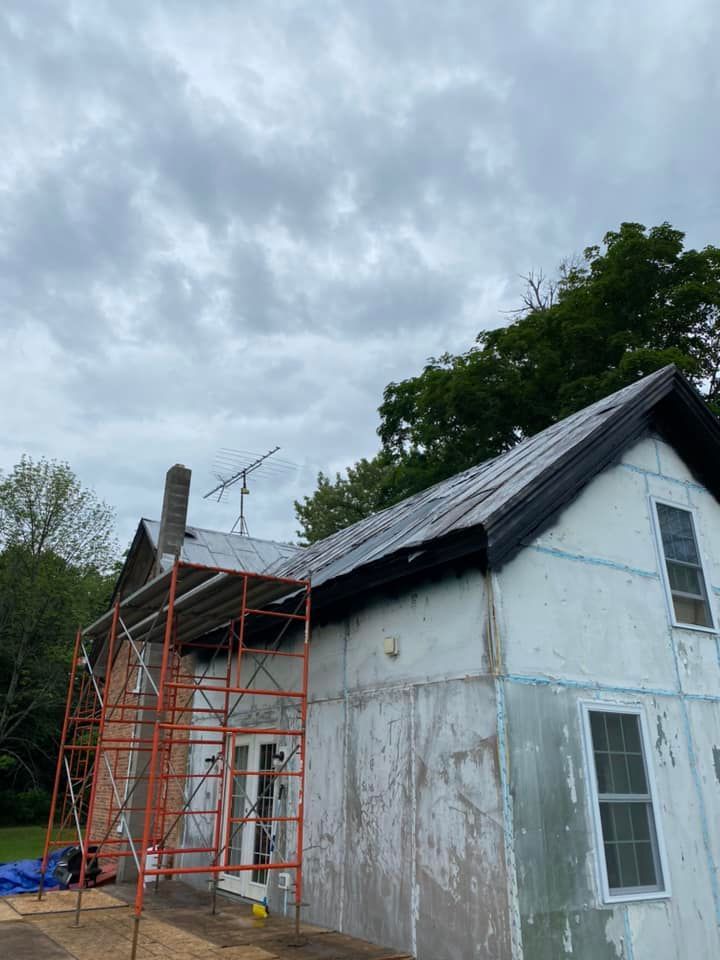 Old white house with peeling paint and orange scaffolding under a cloudy sky