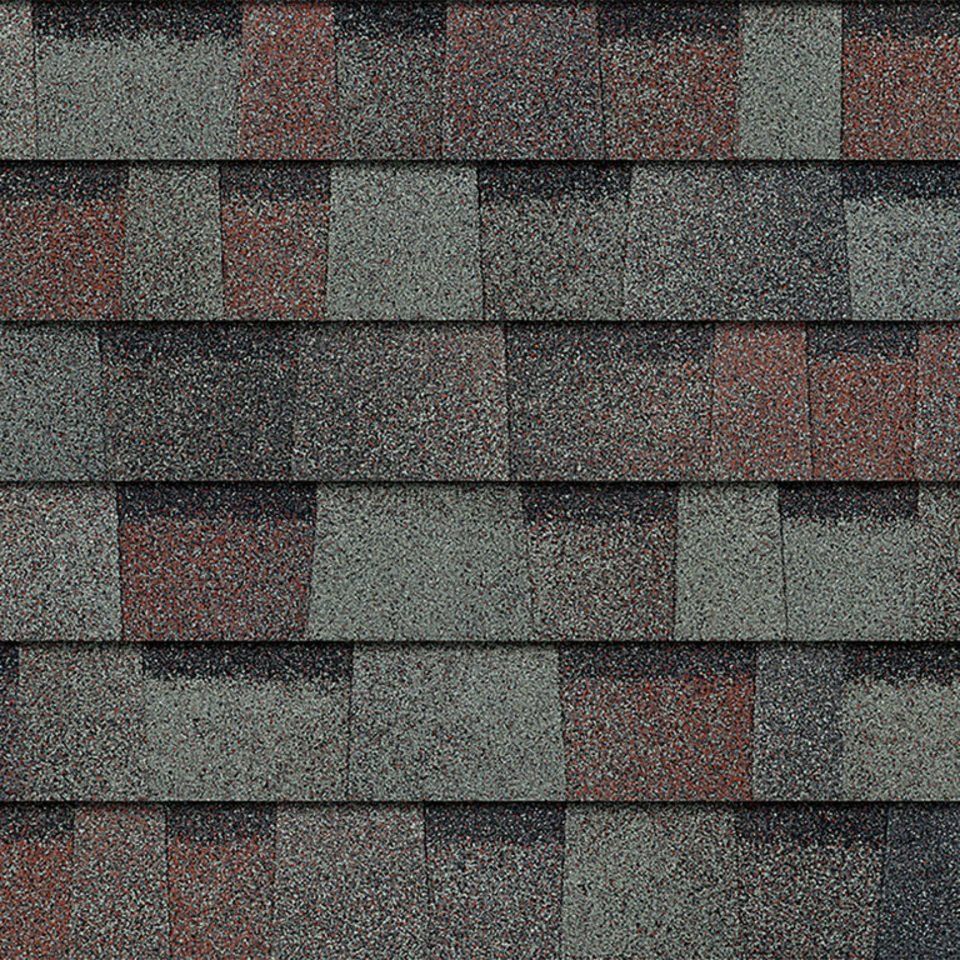 Close-up of weathered gray asphalt roof shingles with scattered red patches