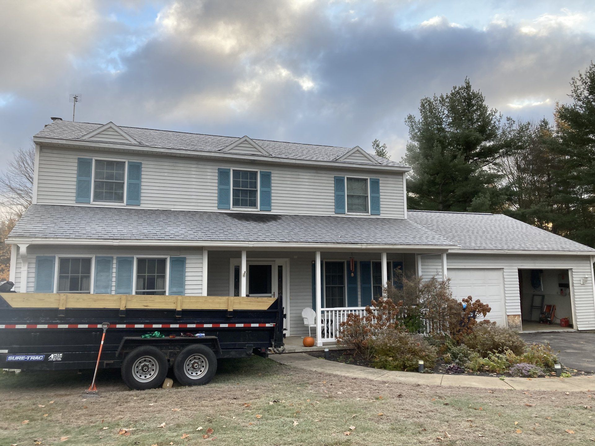 Two-story gray house with white trim and a black trailer parked in front