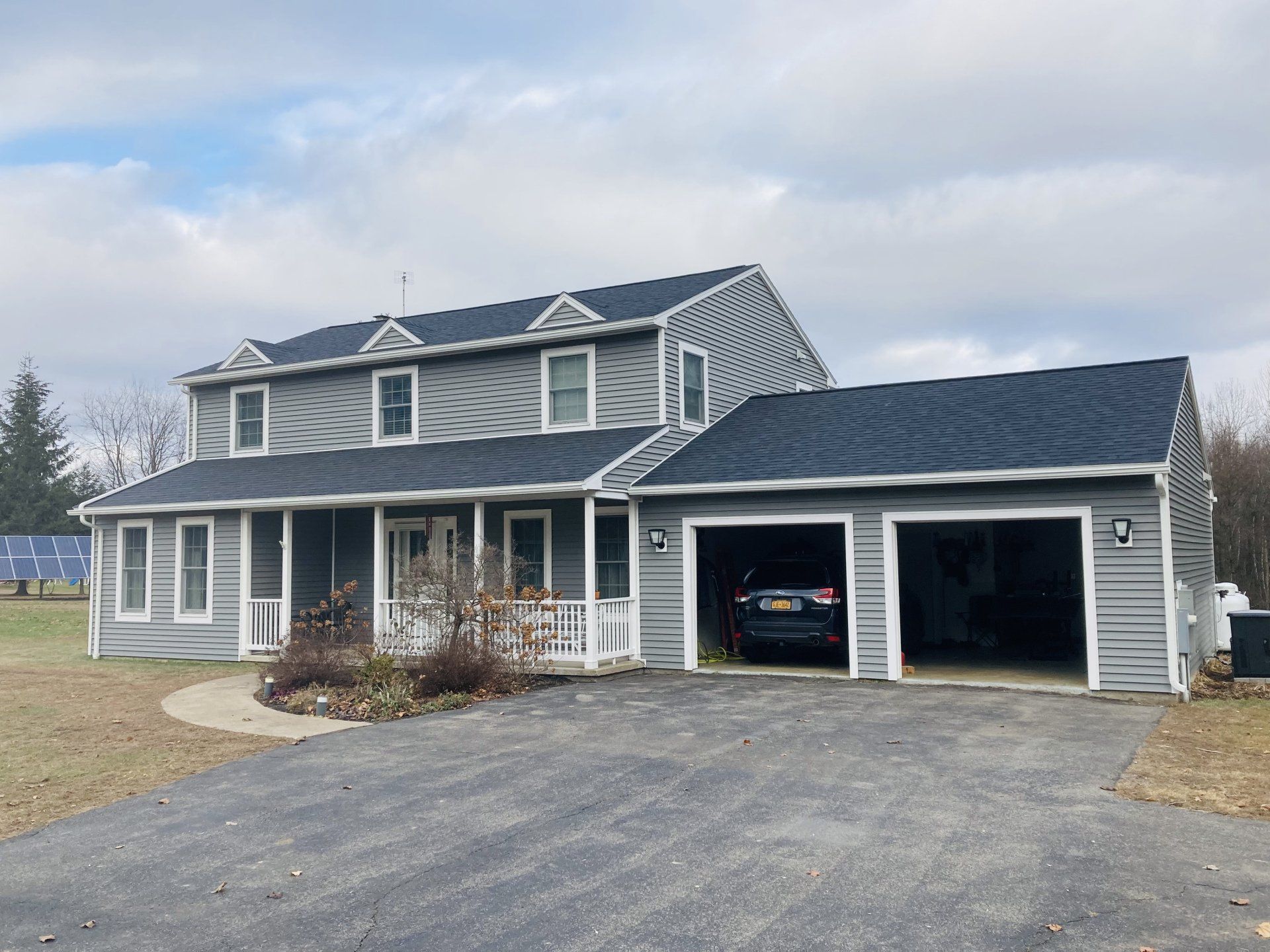 Gray two-story house with attached two-car garage and paved driveway under cloudy sky