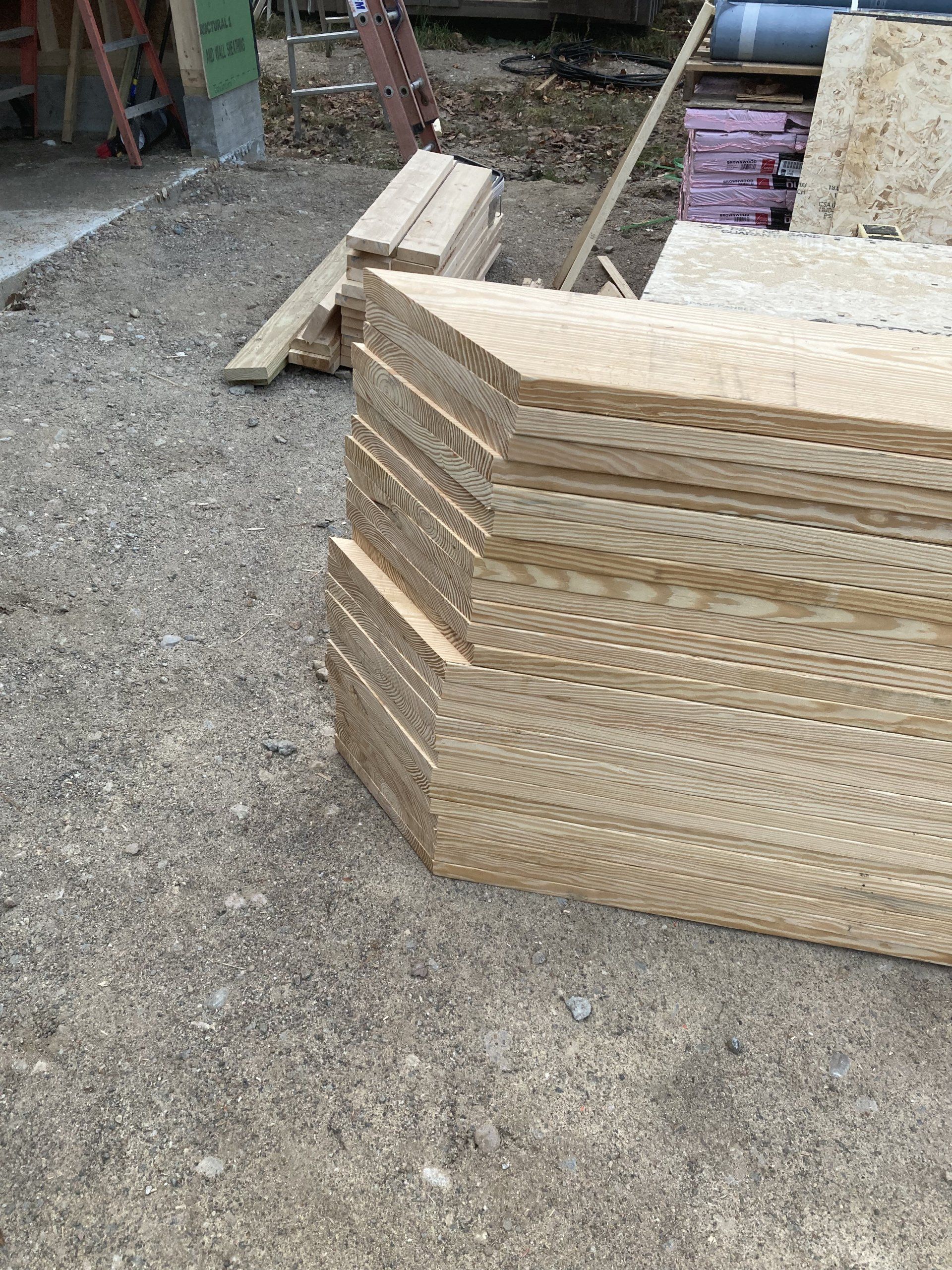 Stacked wooden pallets beside construction materials on gravel ground.