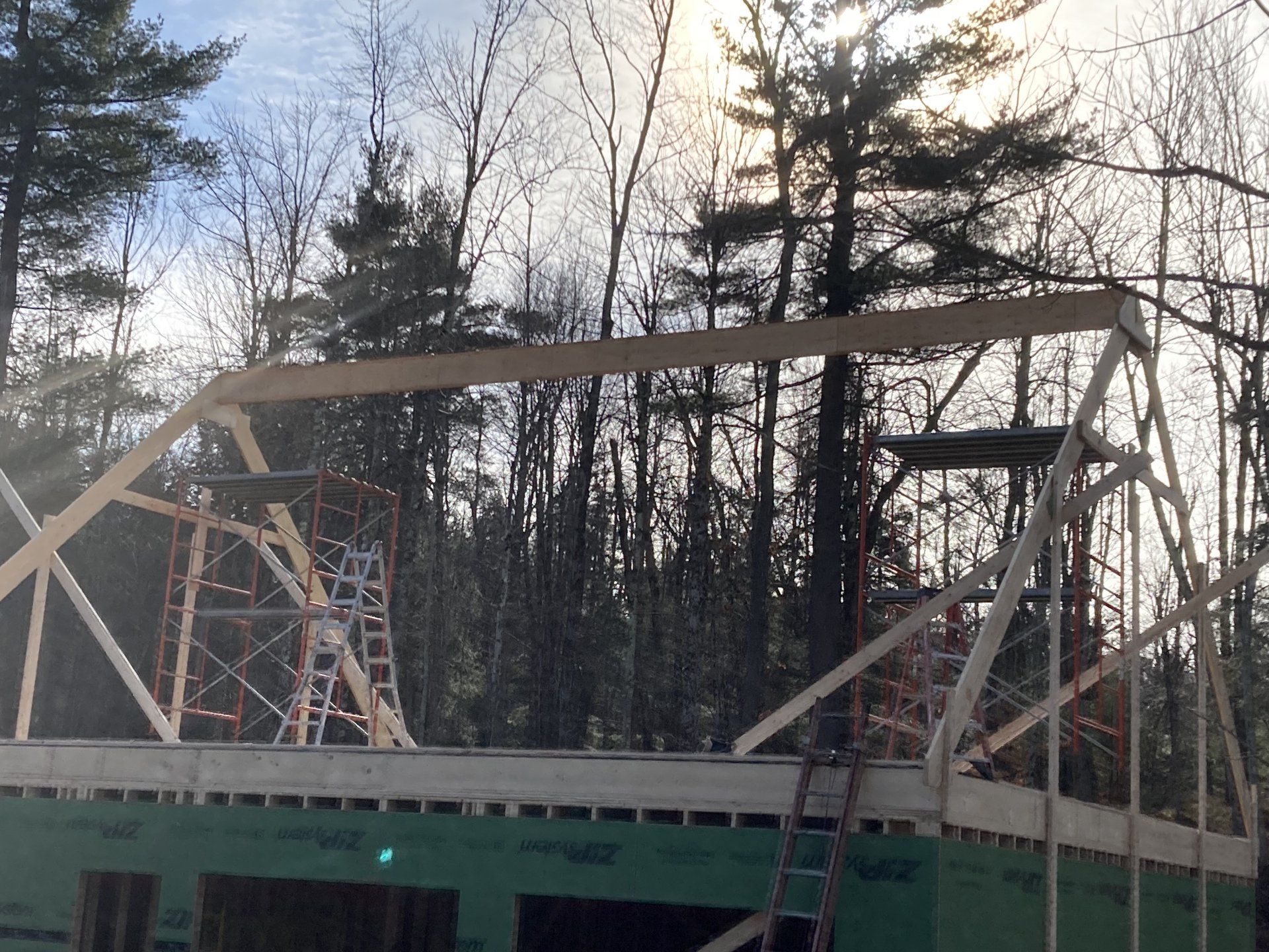 Steel truss bridge under construction at dusk, with trees and a partly cloudy sky in the background