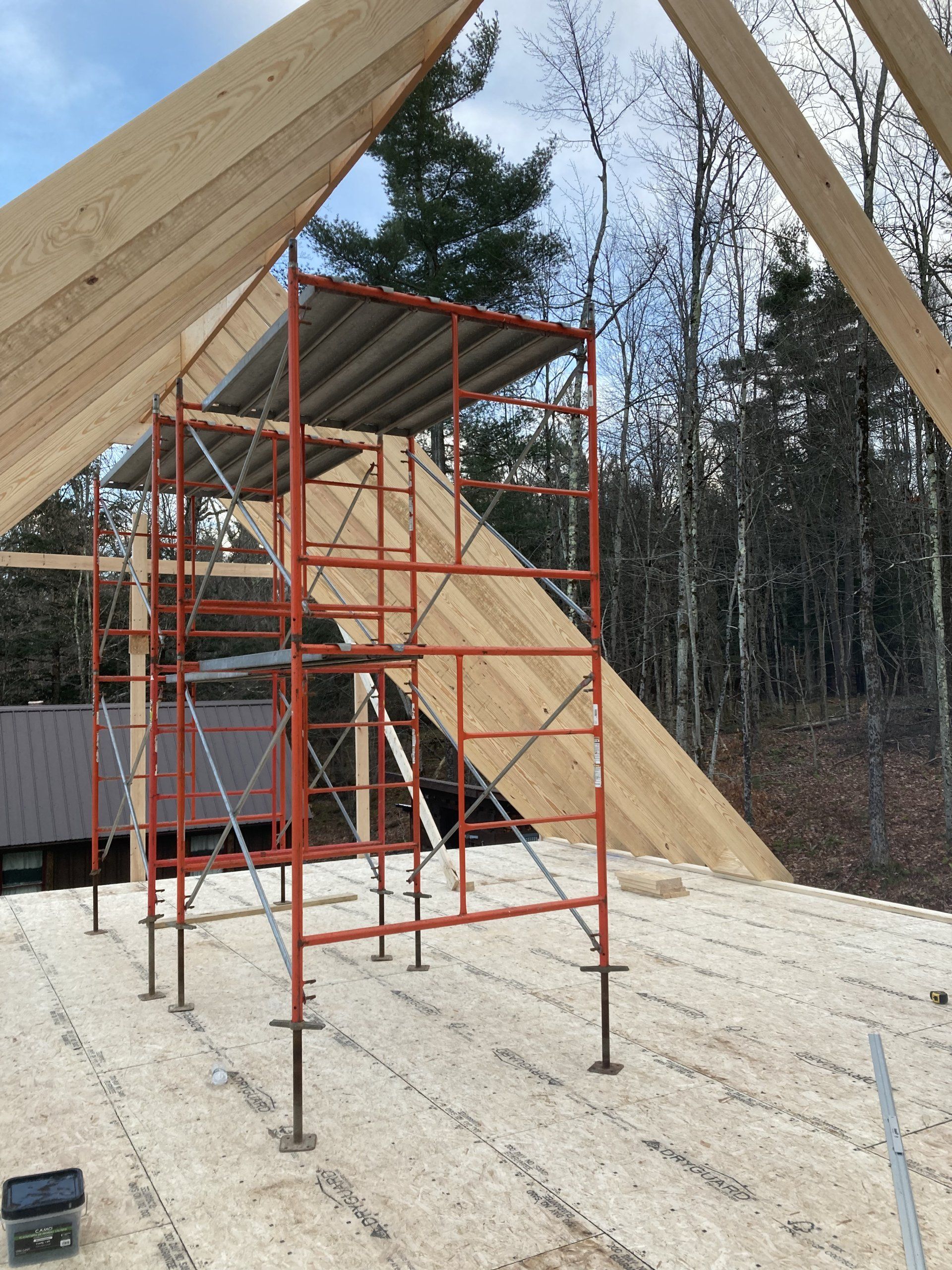 Red scaffolding under a large wooden A-frame on a snowy construction site