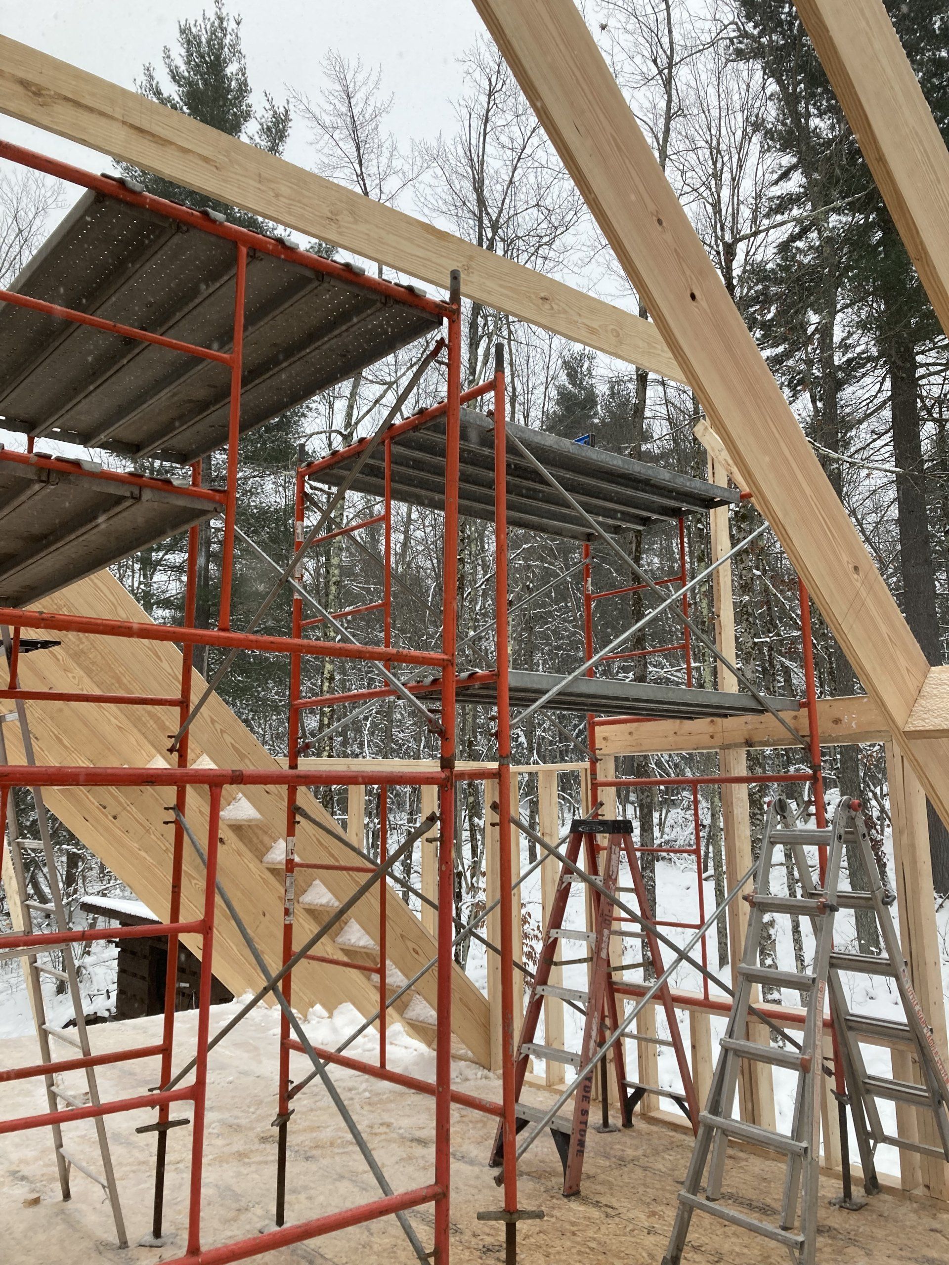 Scaffolding and wooden roof trusses at a snowy construction site