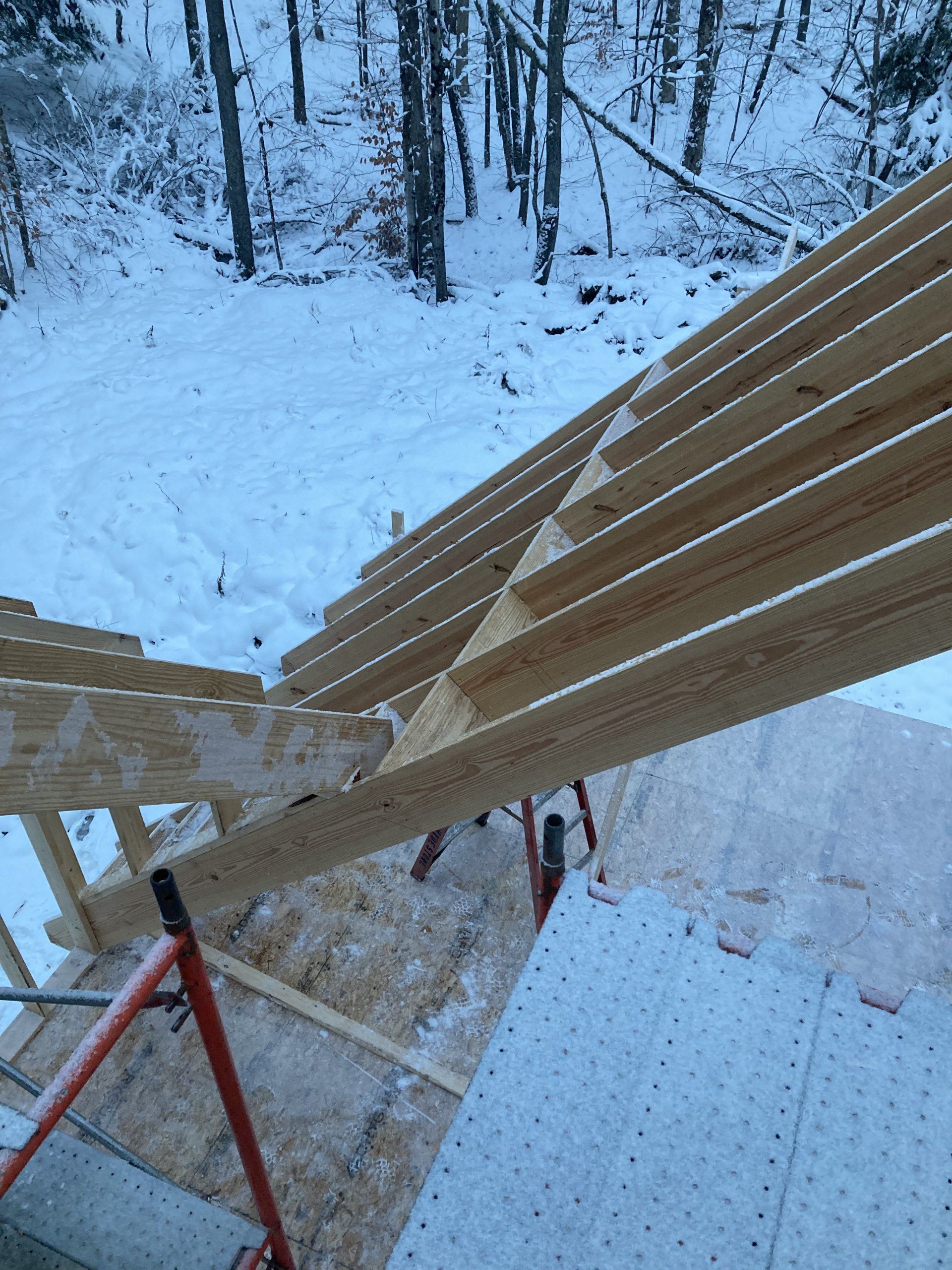 Wooden roof frame under construction in a snowy forest