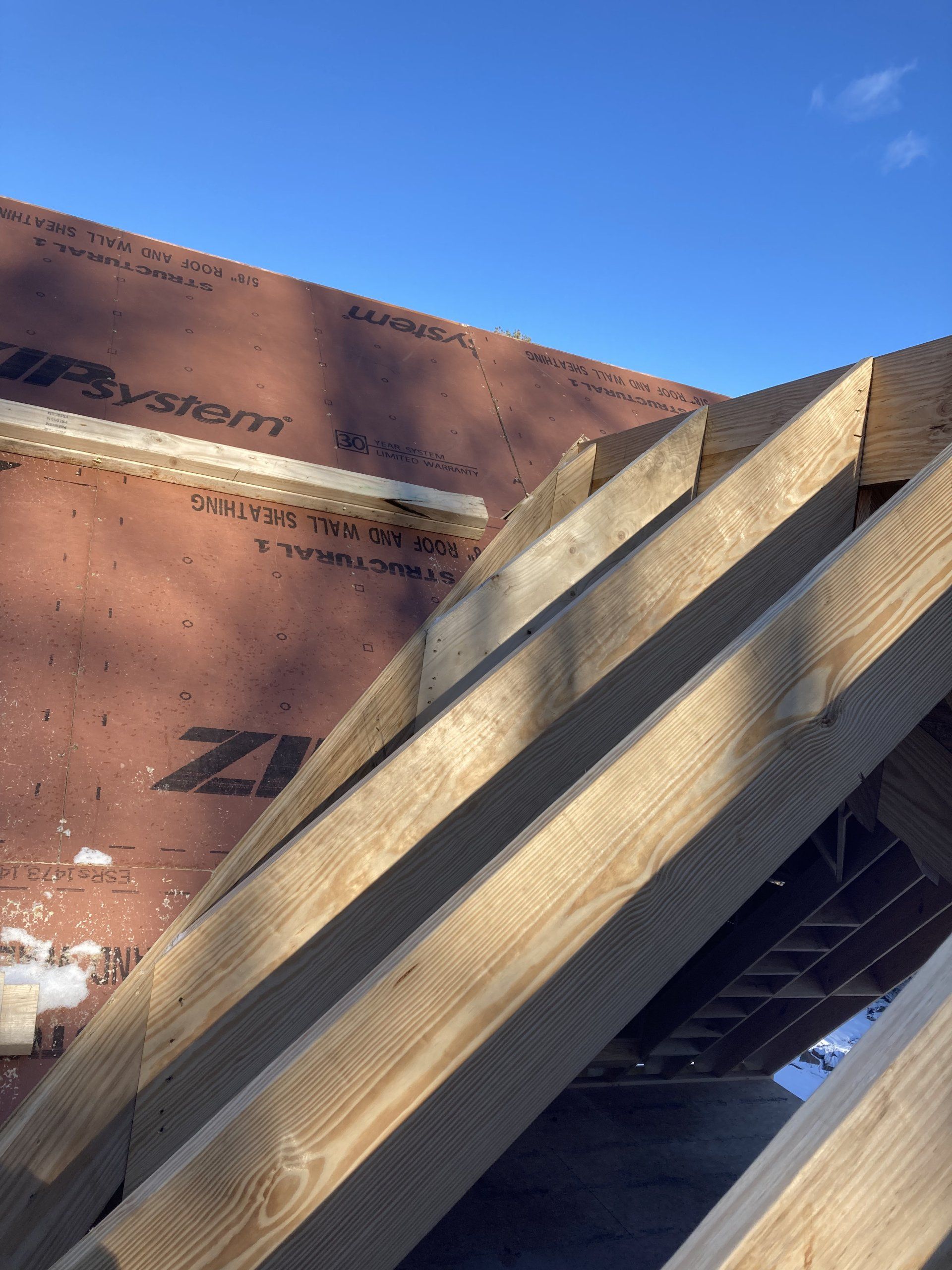 Wooden beams leaning against a brown building under a clear blue sky