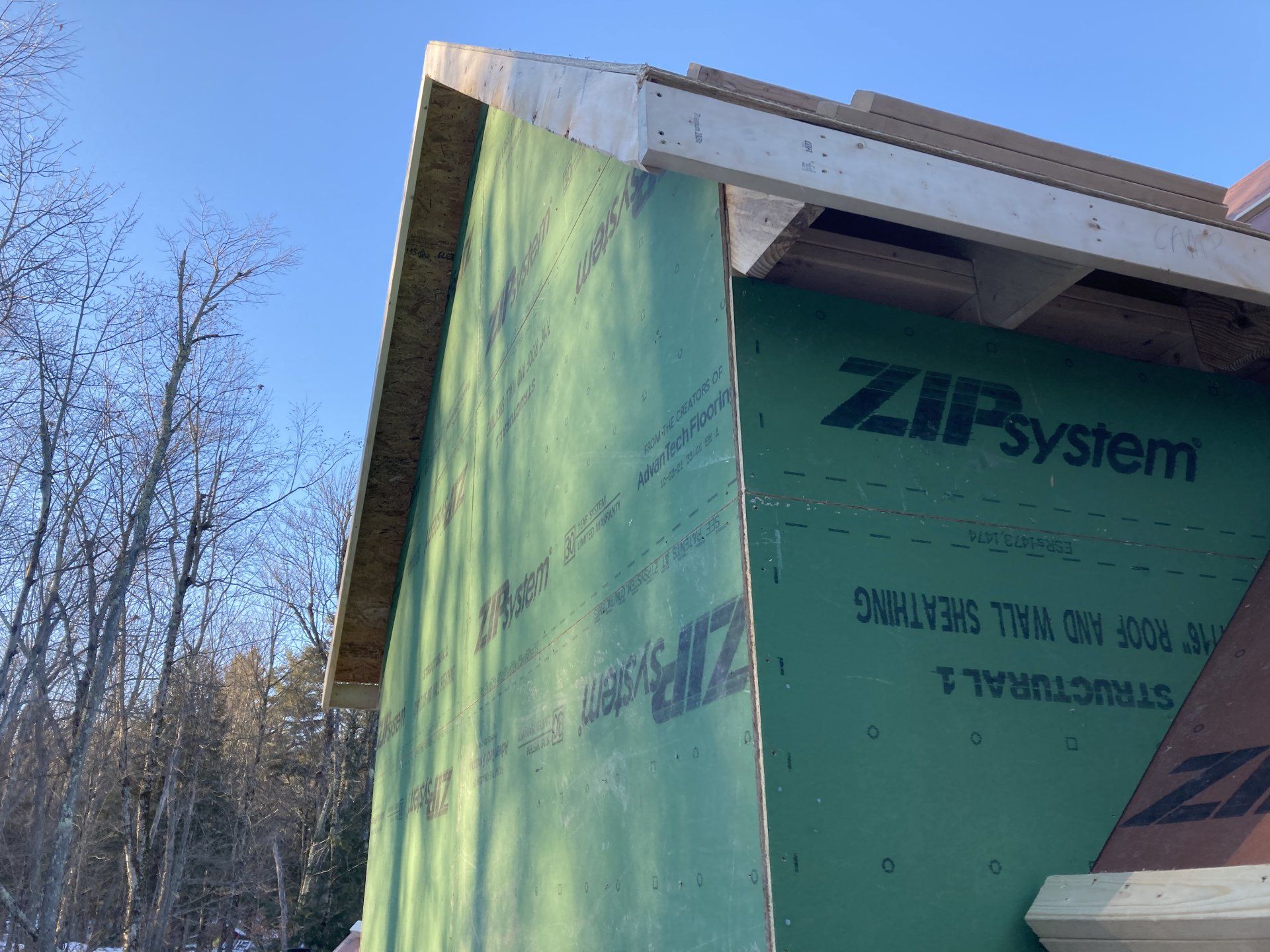 Green ZIP System house wall under construction with exposed roof eaves outdoors