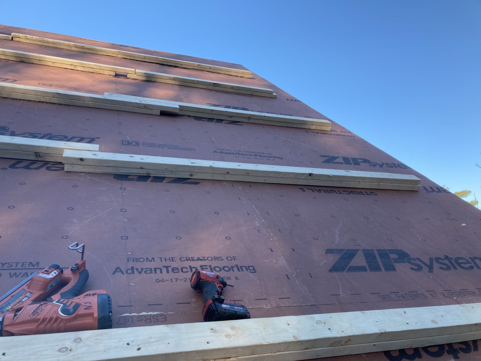 Zip System wall sheathing and house wrap on a tall building under construction against blue sky