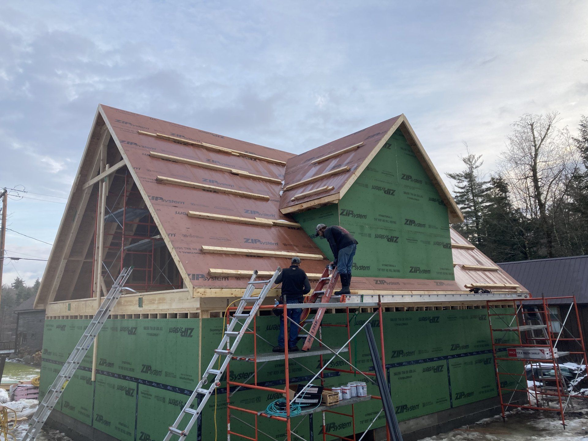 Workers installing roofing on a green house under construction with ladders and scaffolding