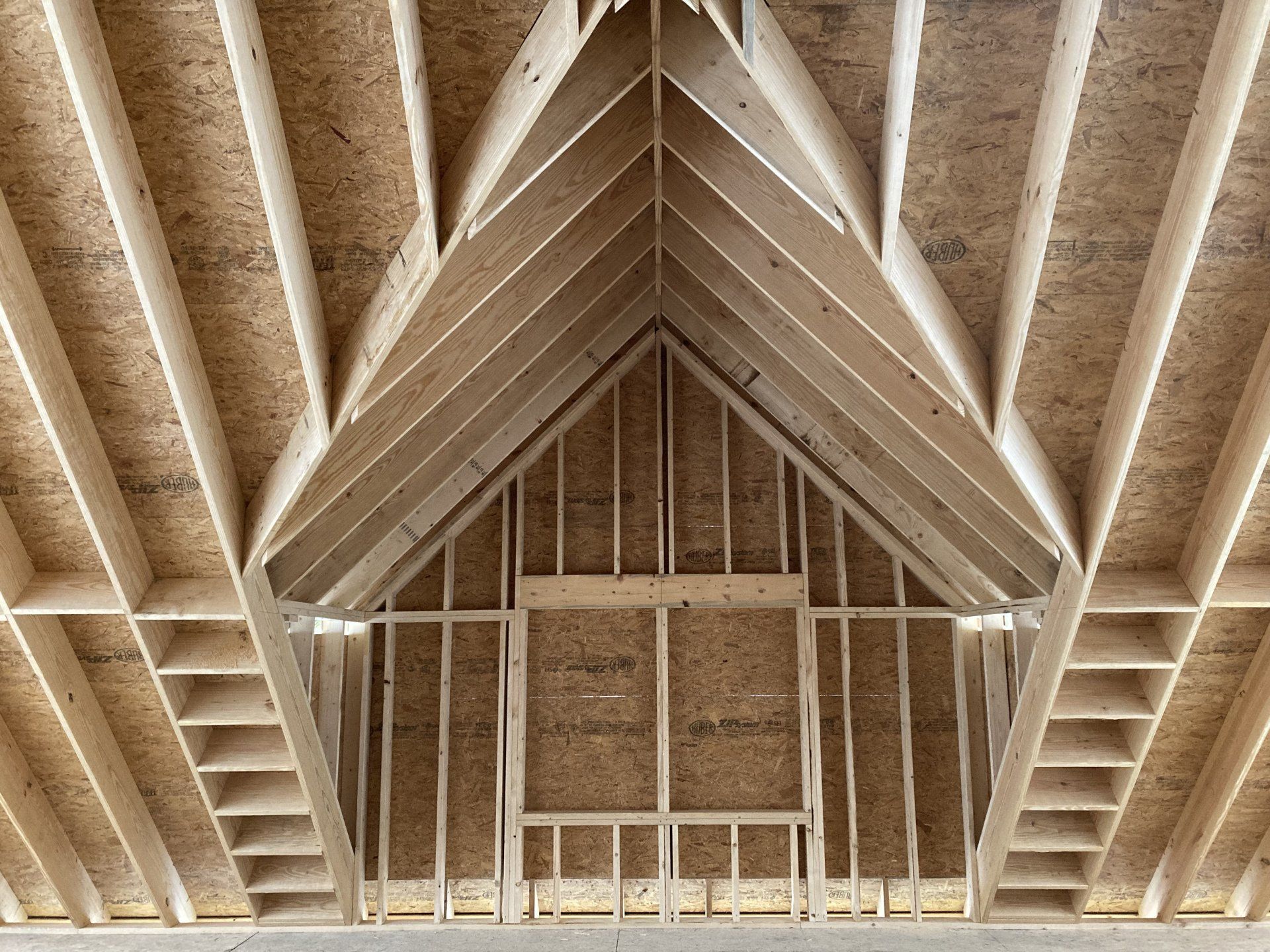 Exposed wooden roof trusses and rafters inside a partially framed attic space