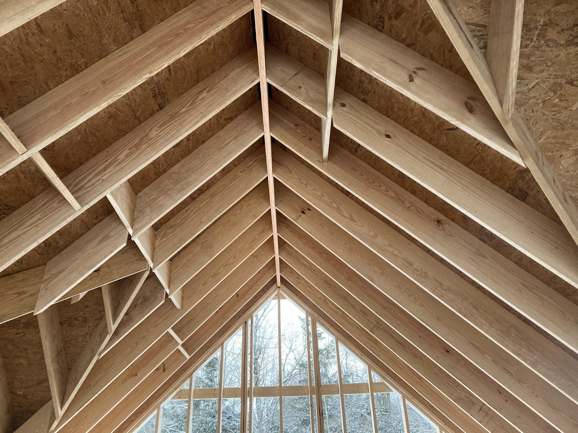 Wooden cathedral ceiling with exposed rafters and a large window at the far end
