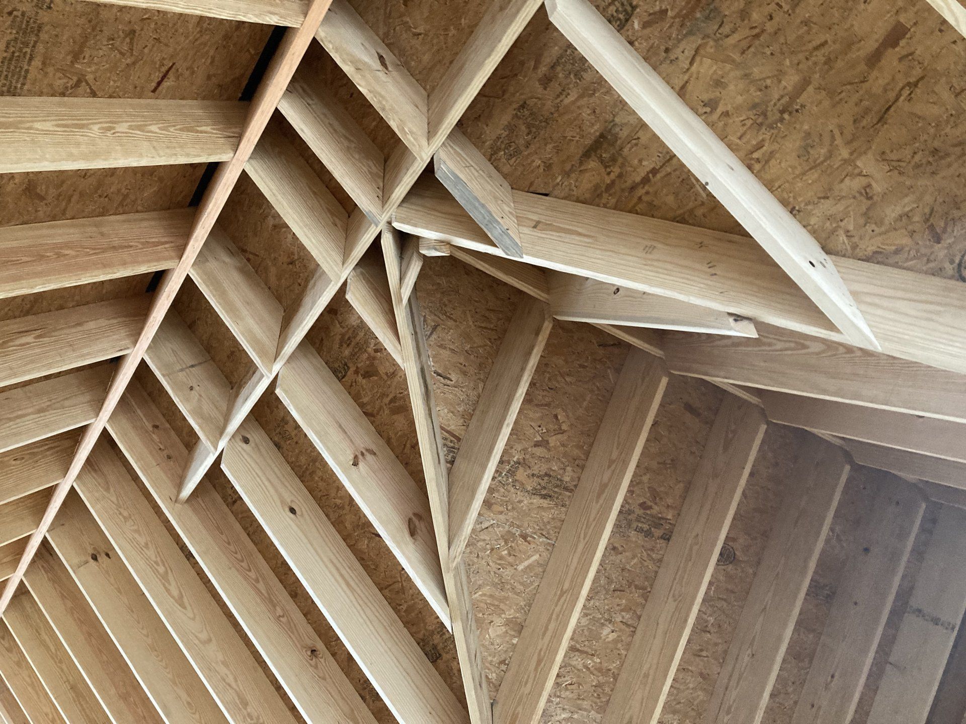 Wooden roof trusses and rafters forming a geometric ceiling structure
