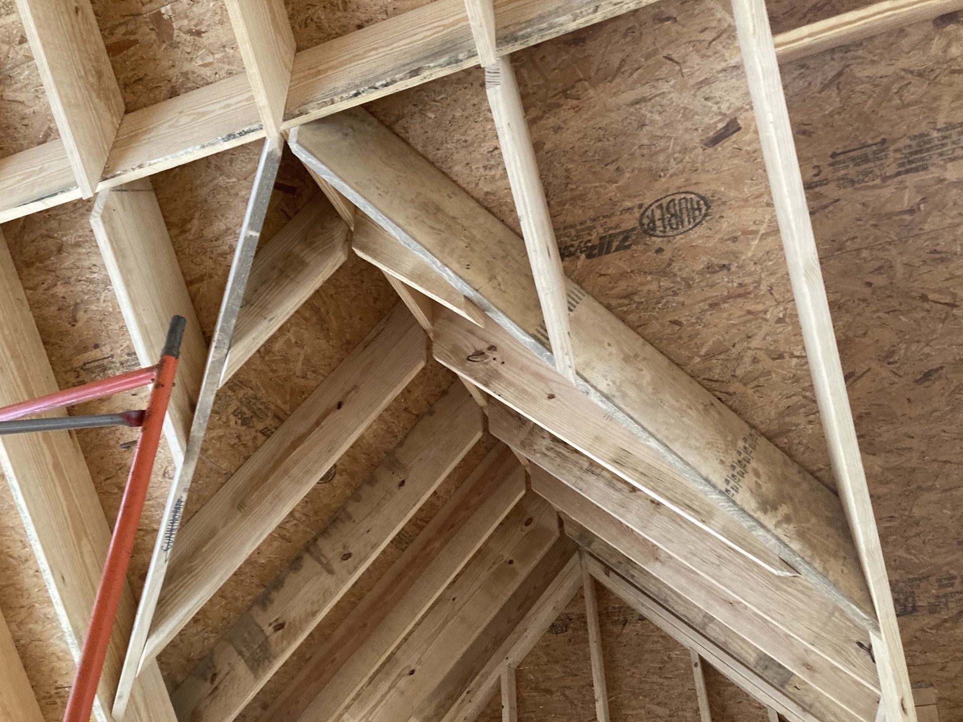 Wooden attic roof framing with exposed rafters and trusses, viewed from below