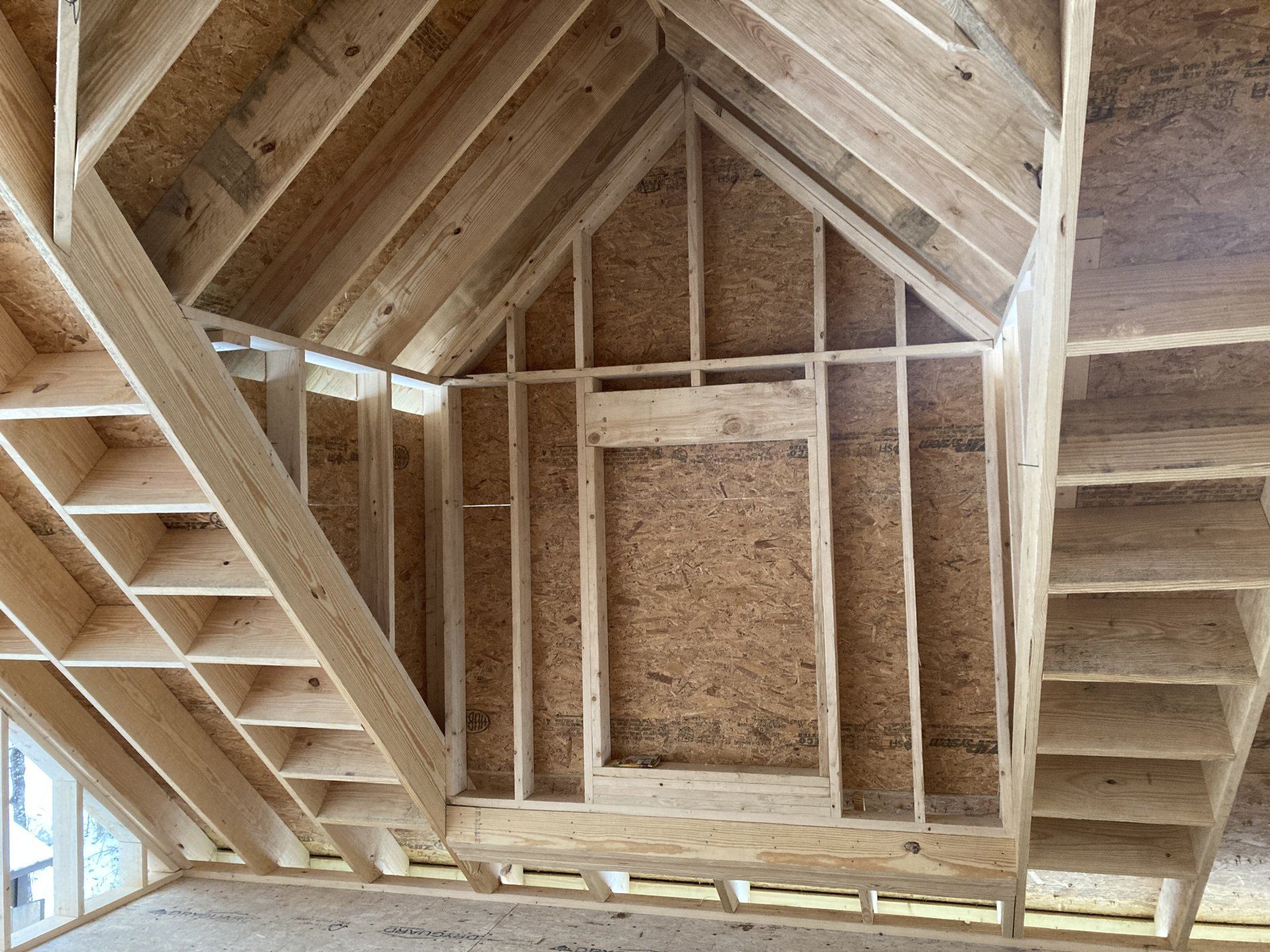 Interior view of unfinished attic framing with exposed wooden rafters and roof trusses