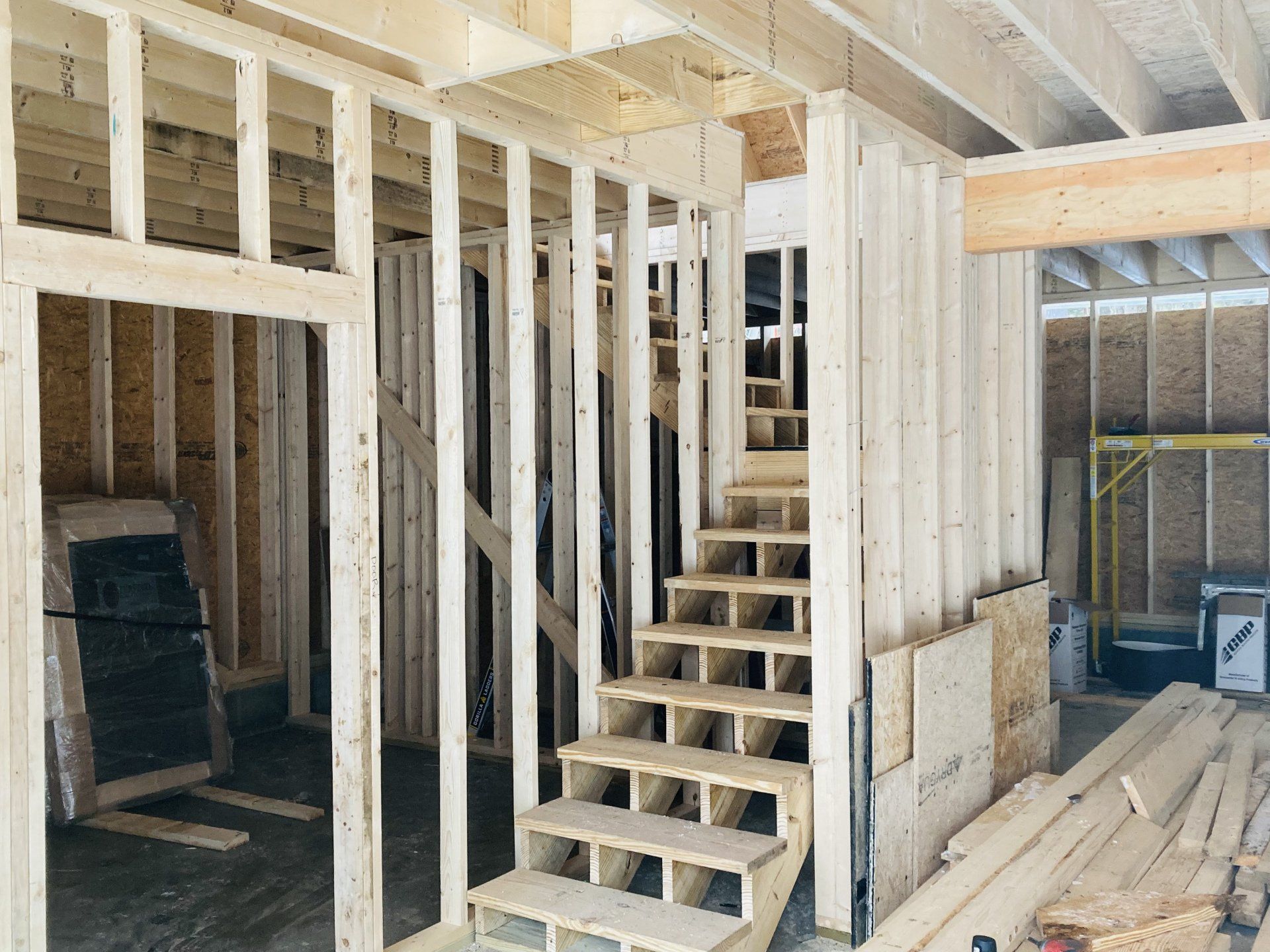Unfinished interior framing with wooden stairs and exposed beams in a construction site