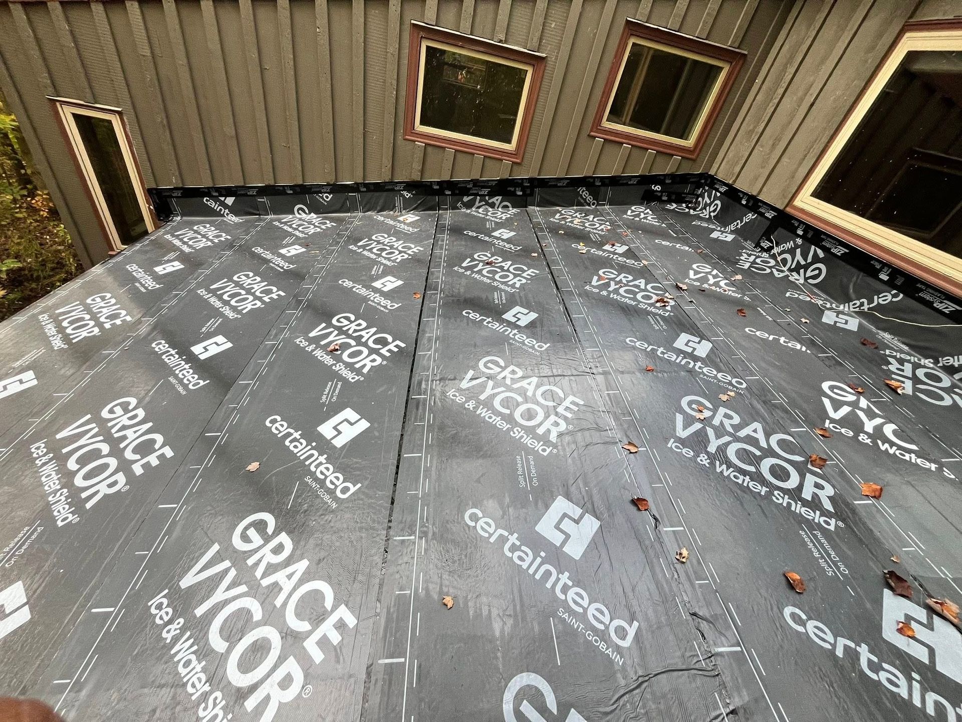 Empty room with dark flooring underlayment printed with logos and wall insulation panels.