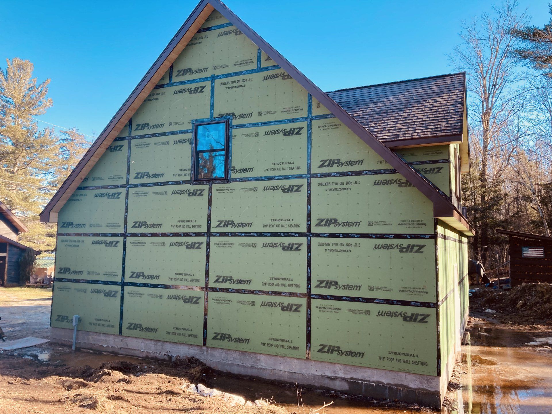 Partially renovated house exterior with green house wrap and a small upper window