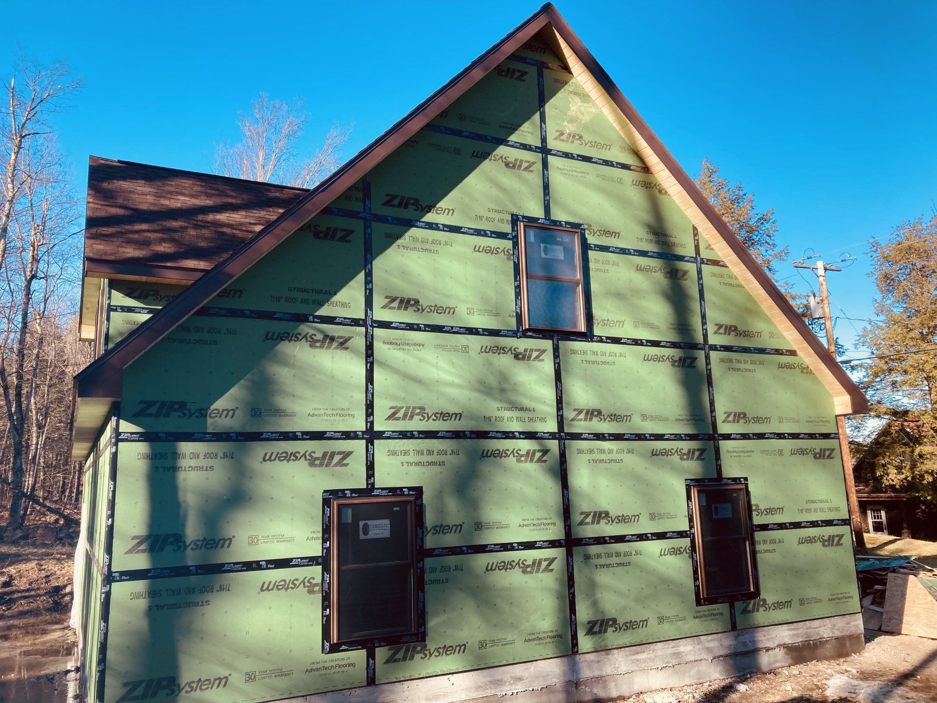 Partially renovated green house exterior with black trim and two windows