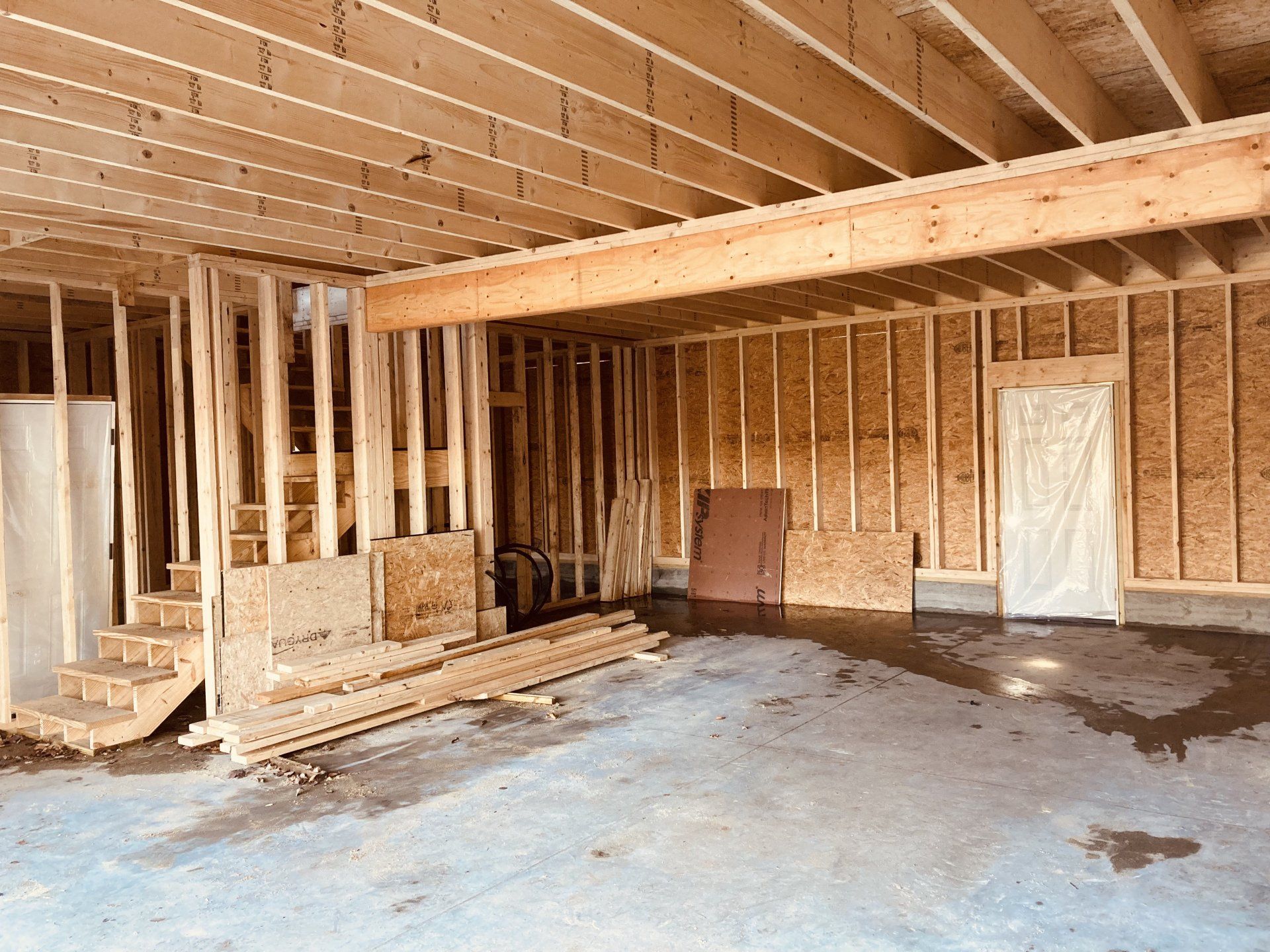 Unfinished framed basement with exposed wood studs, stairs, and concrete floor