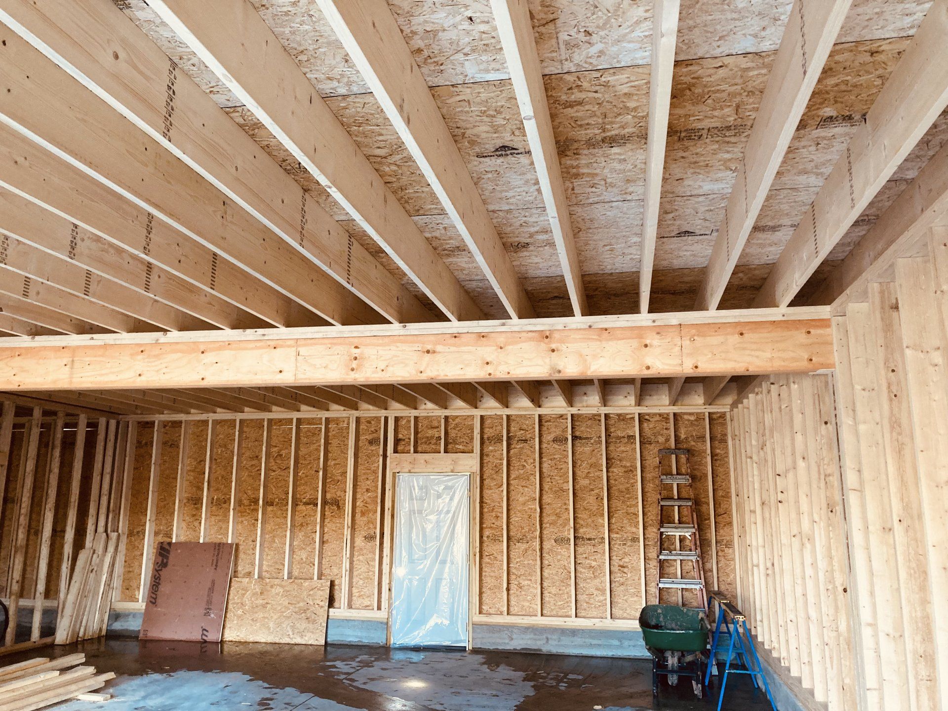 Interior of a framed room under construction with exposed wood studs, beams, and insulation panels