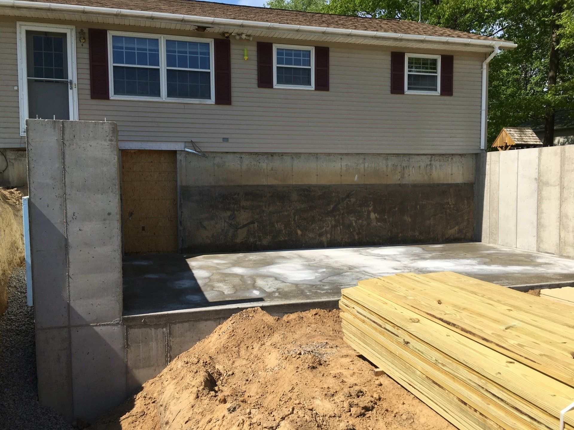 House with a new concrete driveway and stacked lumber in the foreground