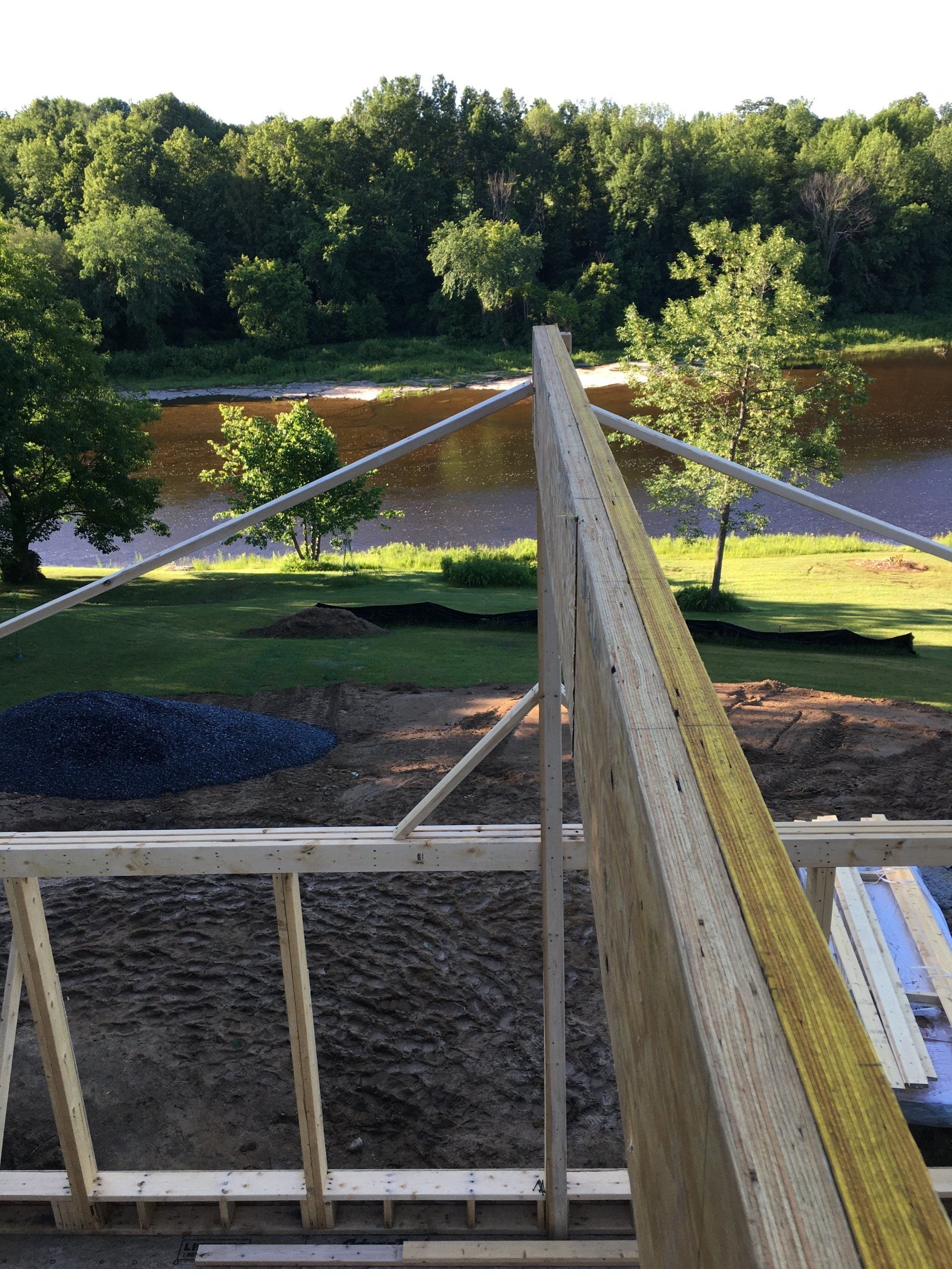 View from a wooden platform over a muddy river, with trees and grassy banks in the background.