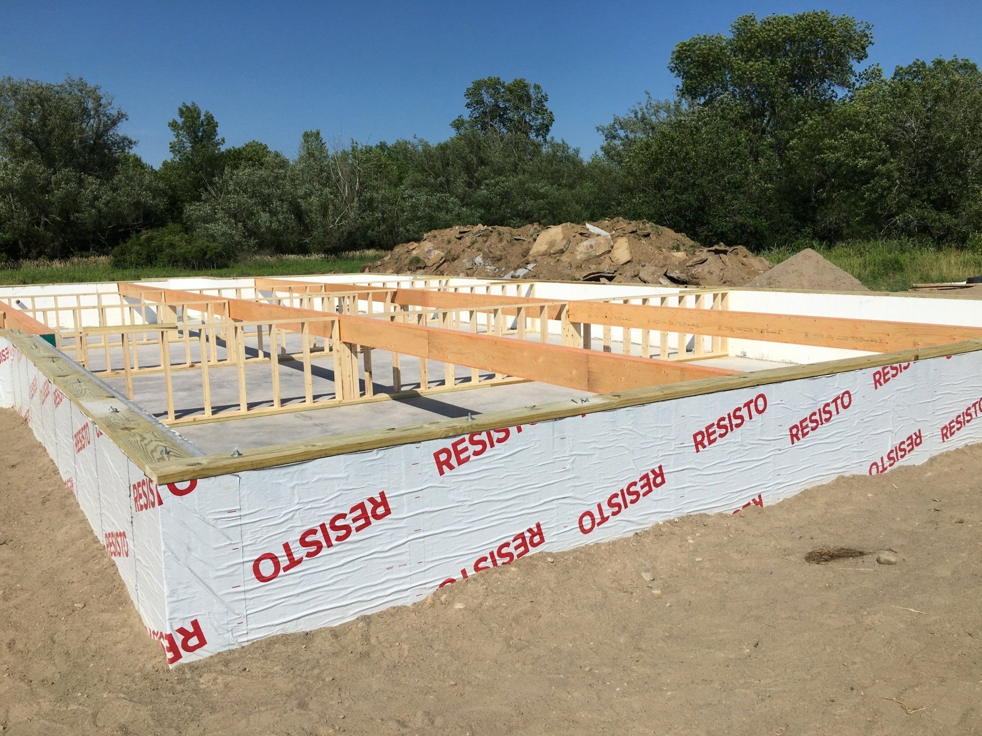Foundation forms and insulation panels laid out at a new house construction site under a clear blue sky