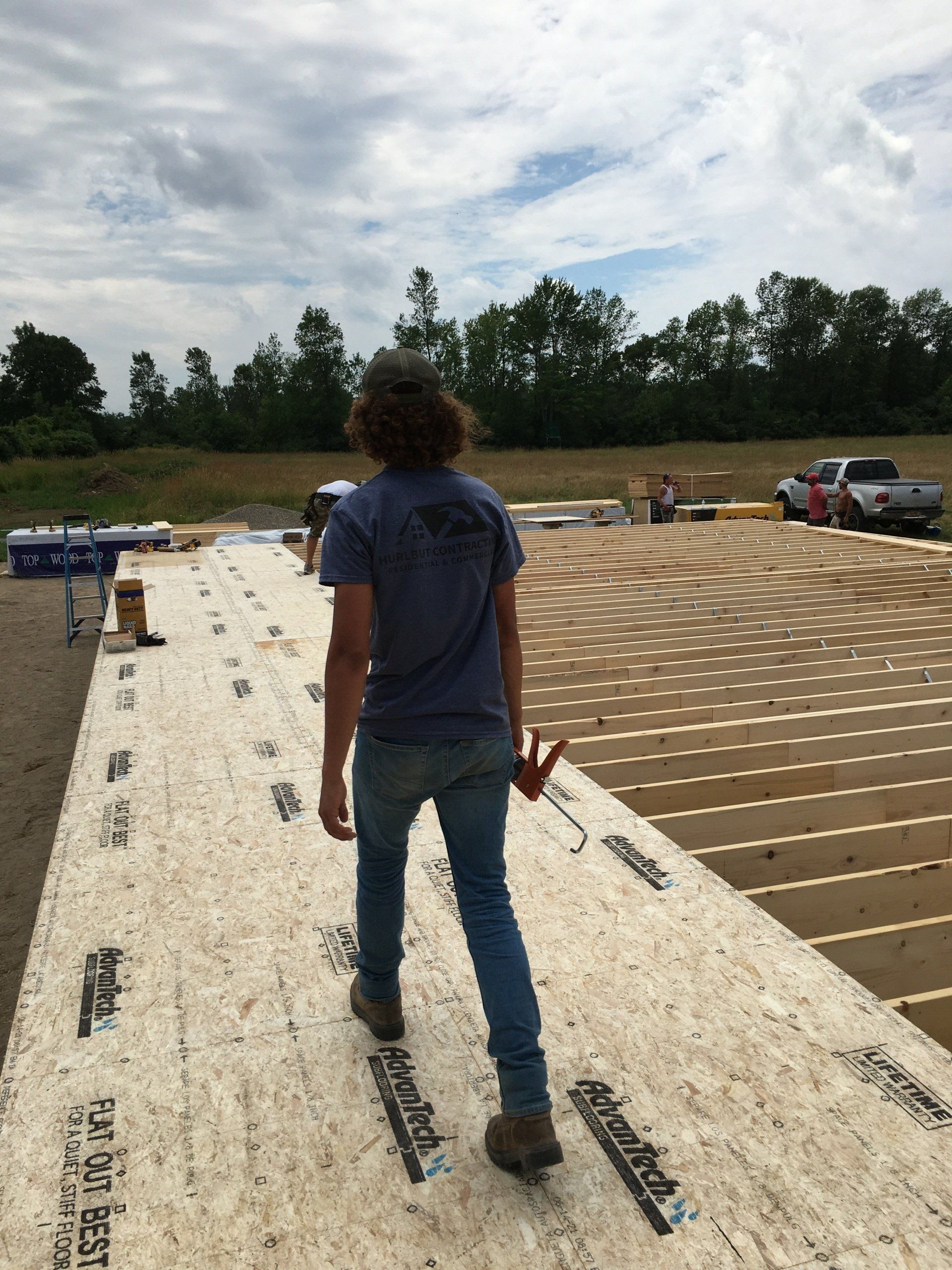Person walking on a rooftop under construction with workers and materials in the background