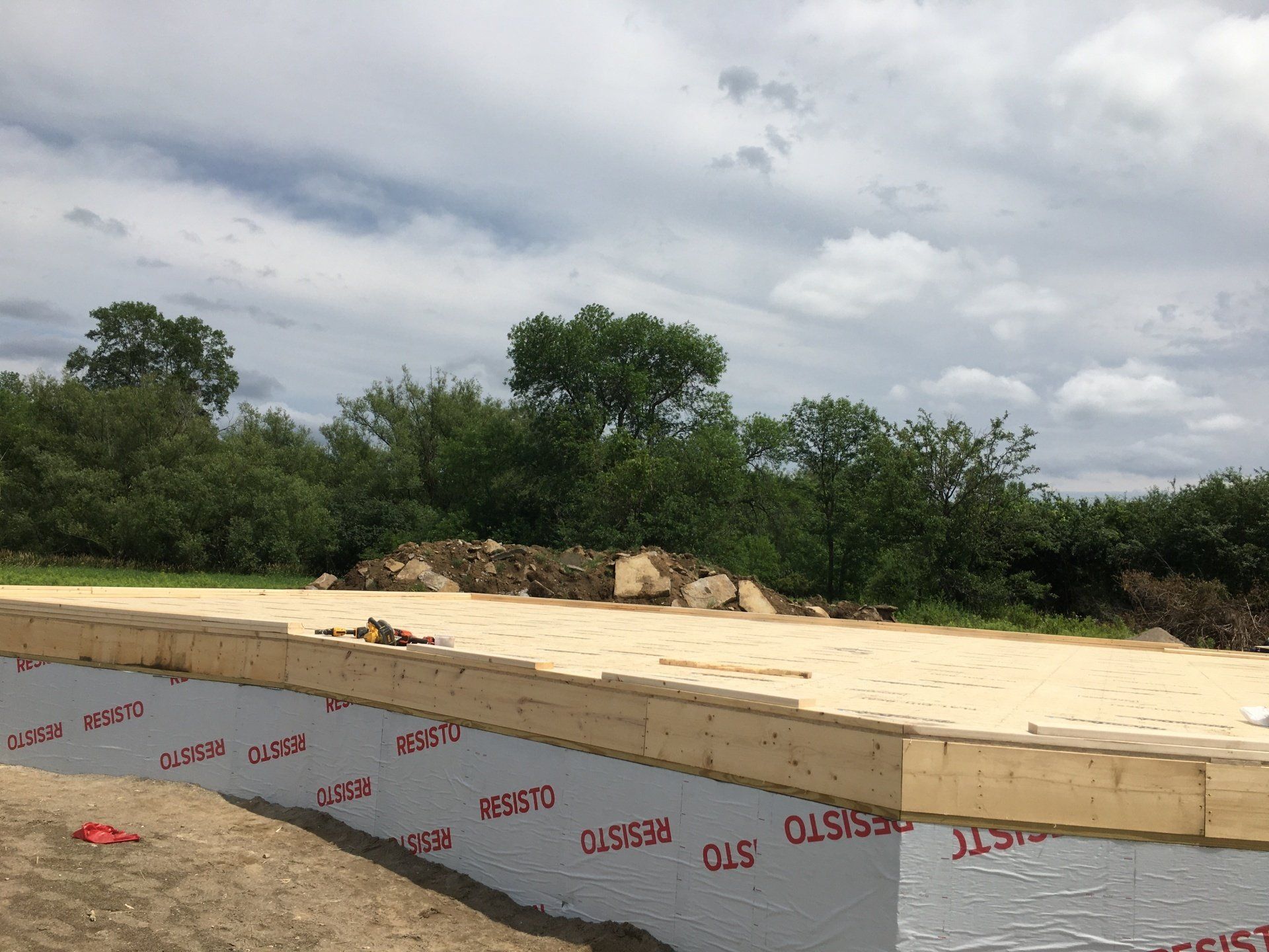 Raised concrete foundation beside trees under a cloudy sky