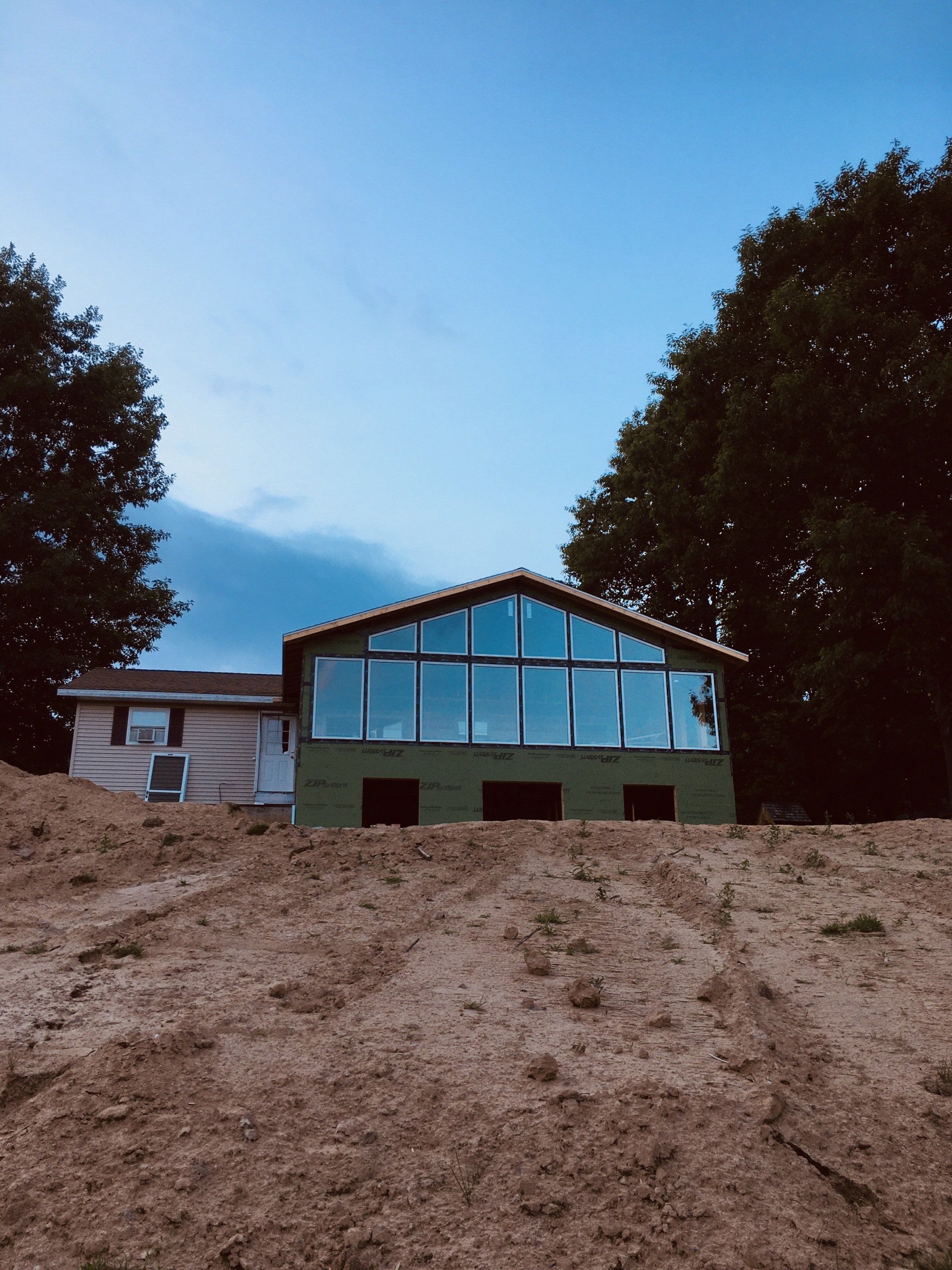 Modern house with large glass windows on a sandy hillside at dusk