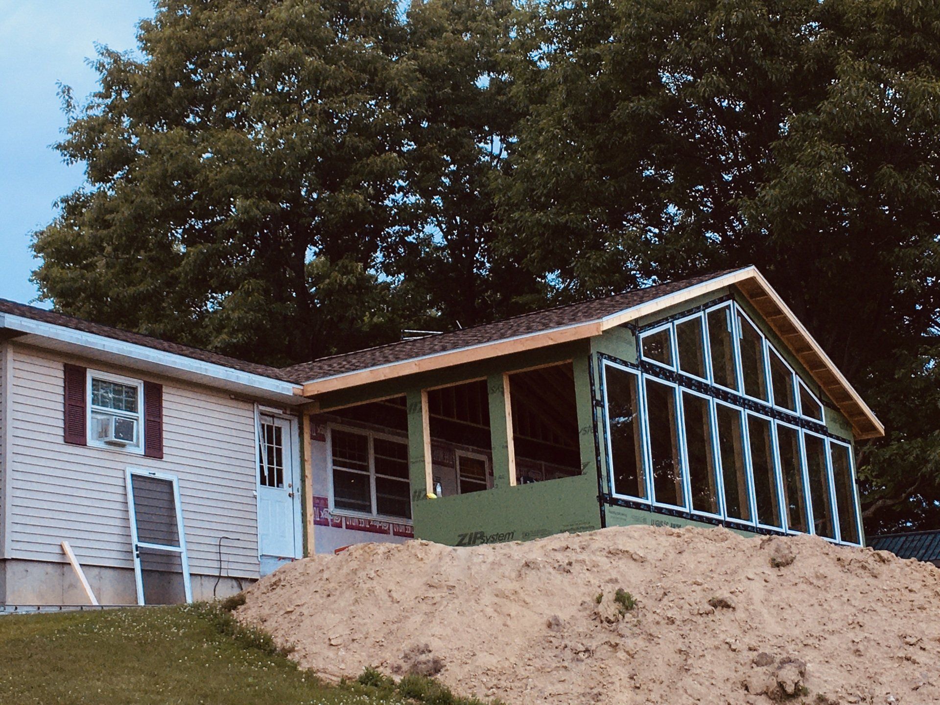 House under construction with a screened-in porch and dirt mound in front