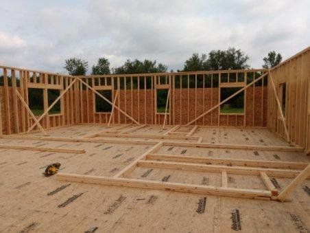 Wood-framed house under construction with exposed studs and floor joists