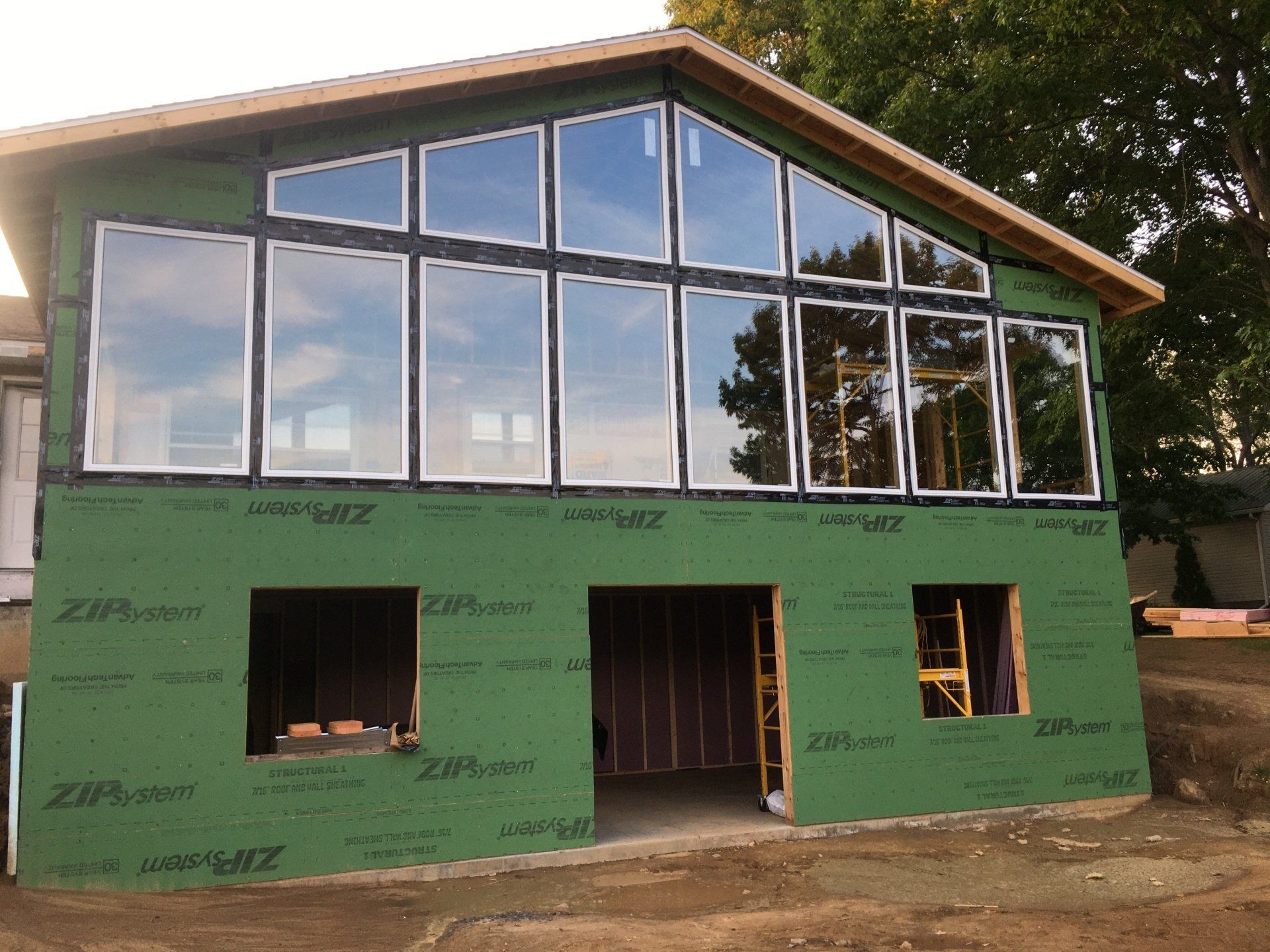 Partially finished two-story house with green wrap and large front windows