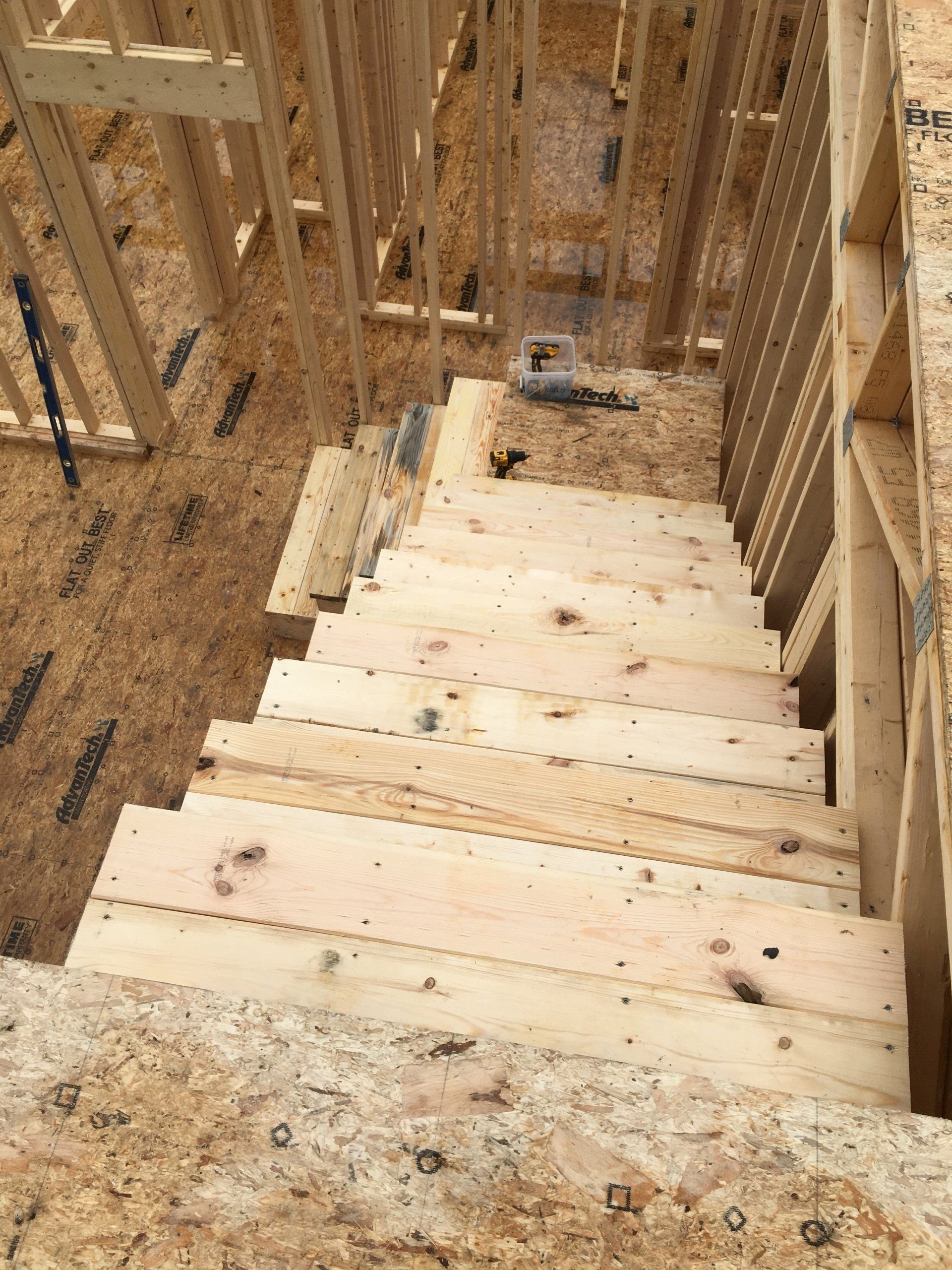 Unfinished wooden staircase descending in a construction framing area