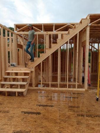Construction worker on wooden stairs at a house frame under construction