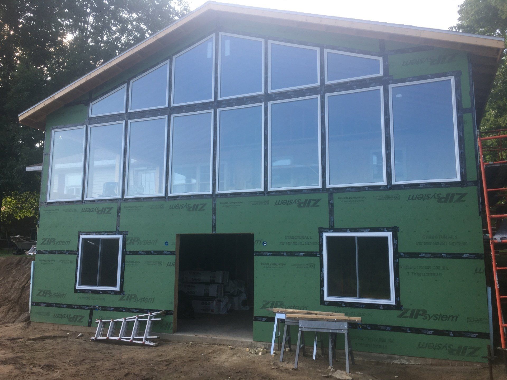 Green house under construction with large front windows and a central doorway.